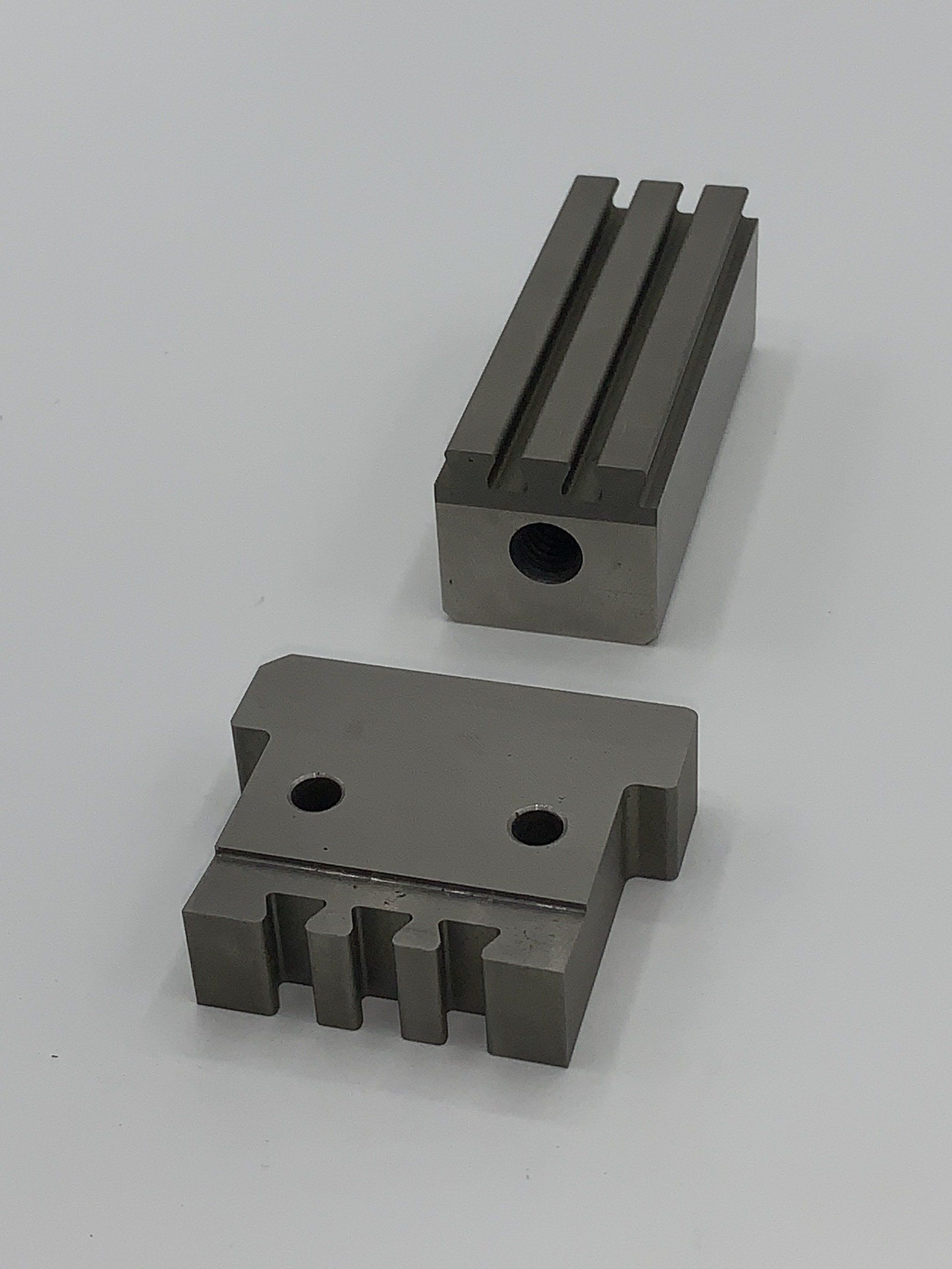 Two pieces of metal are sitting next to each other on a white surface.