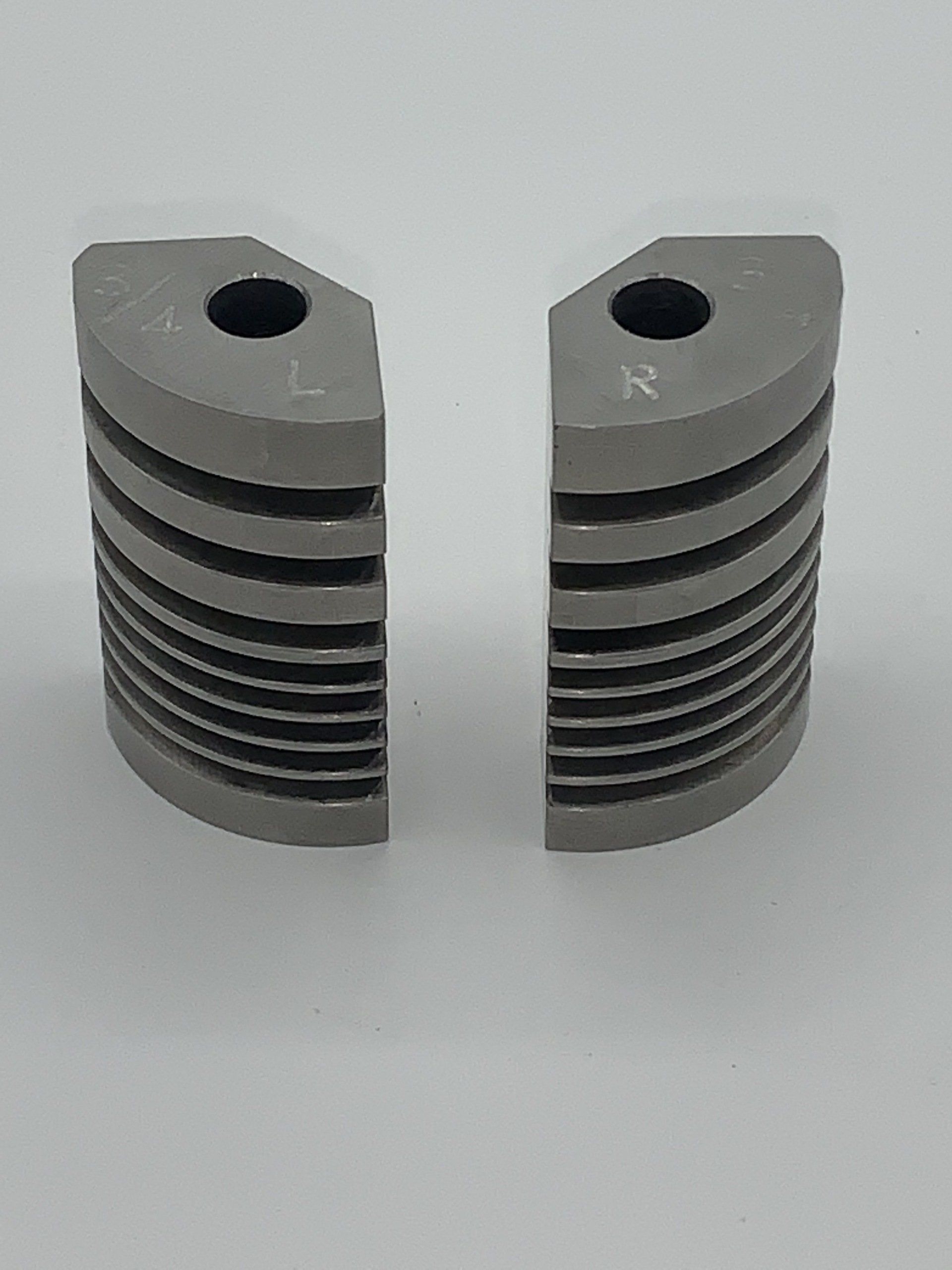 Two pieces of metal with holes in them are sitting next to each other on a white surface.