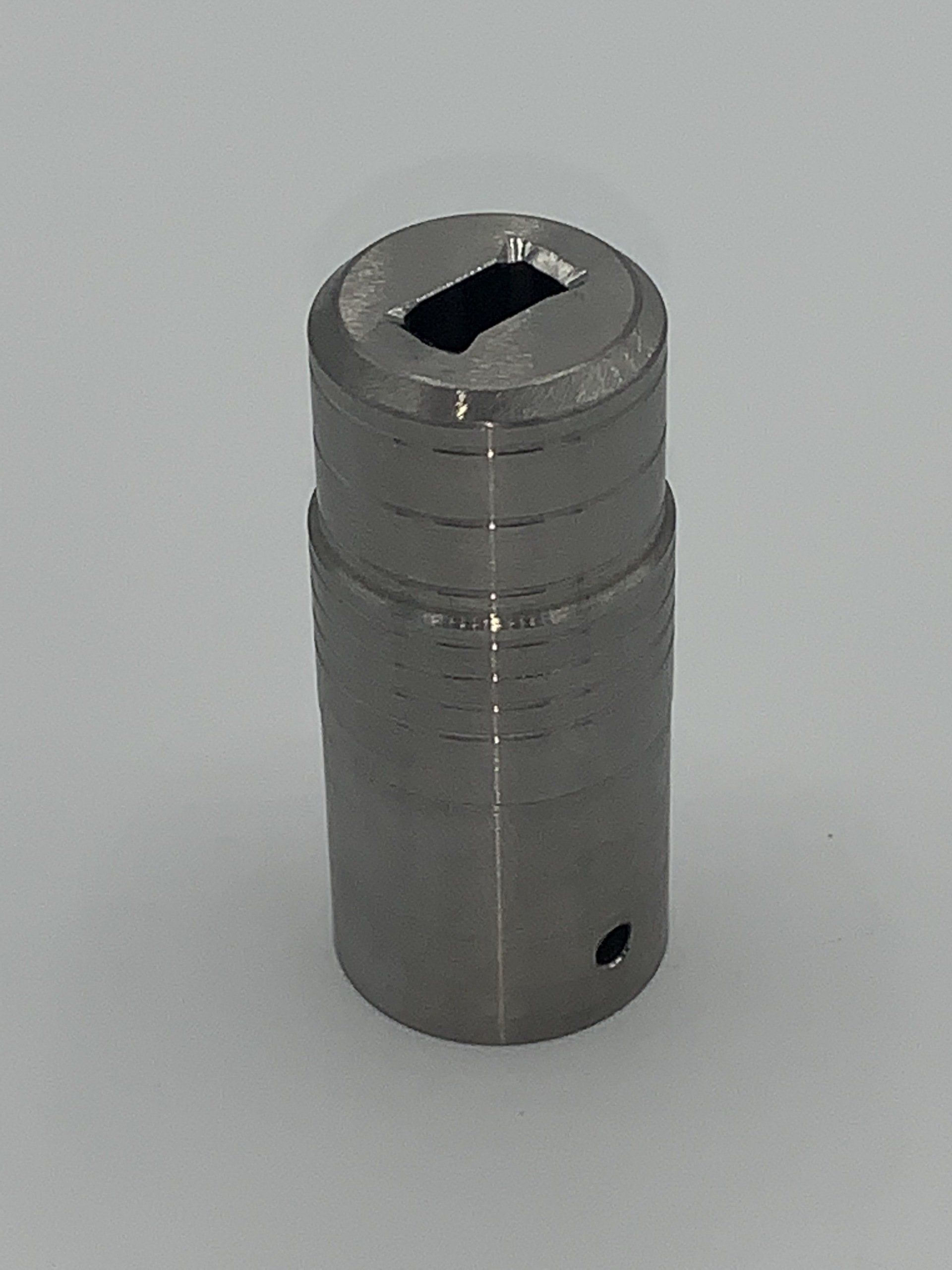 A small metal object with a hole in the middle is sitting on a white surface.