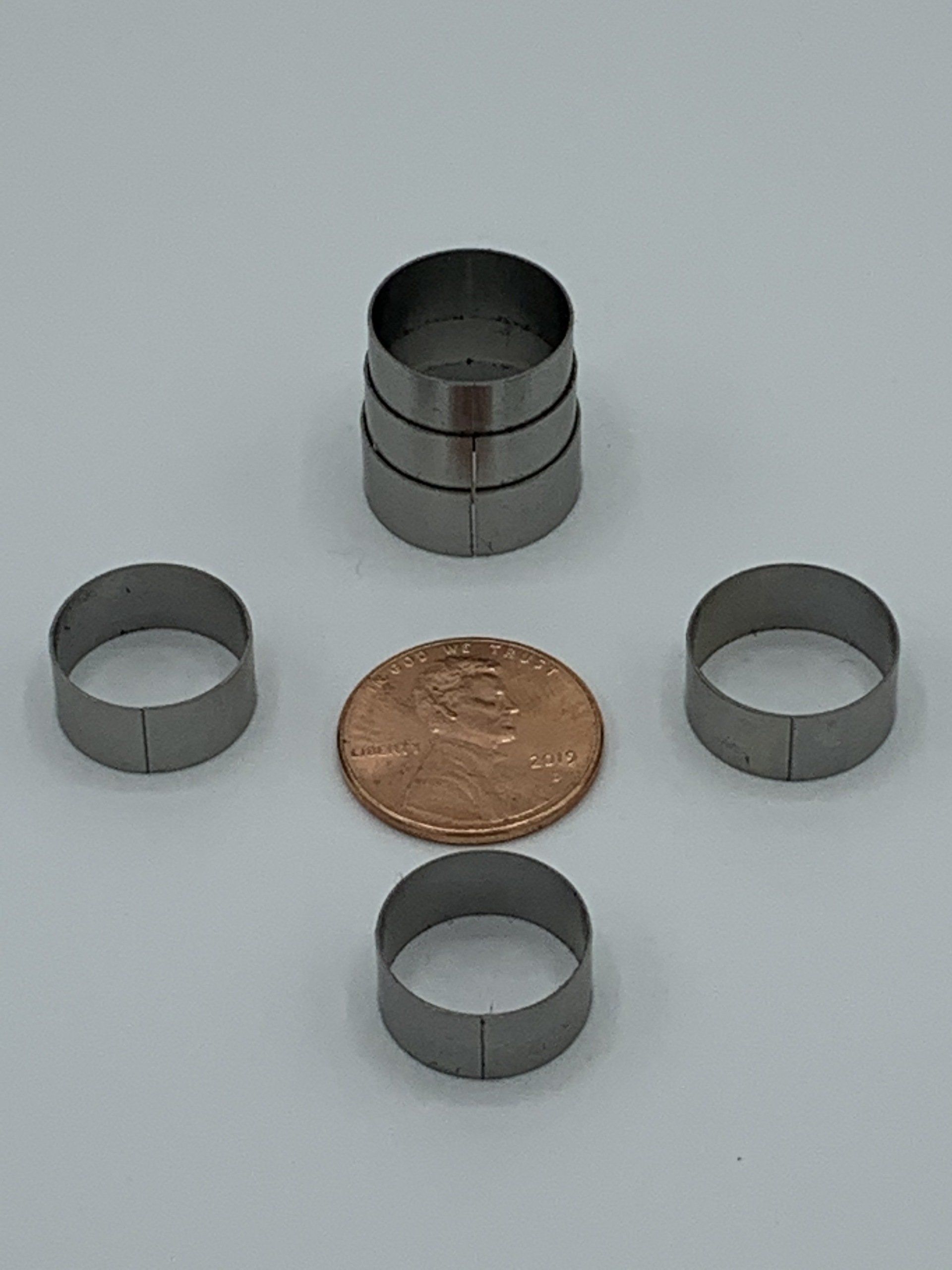 A stack of metal rings next to a penny on a table.