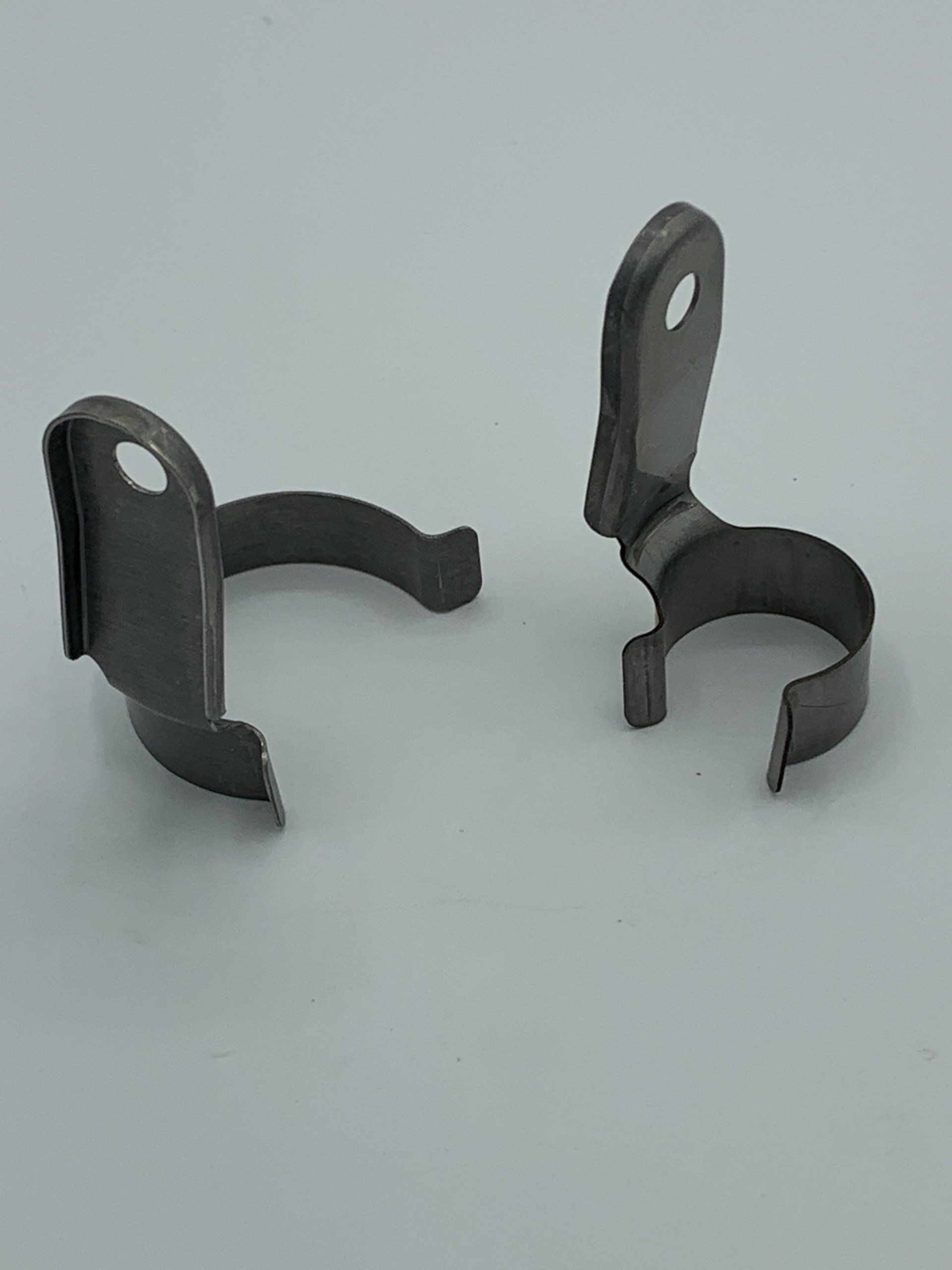 A pair of metal clips are sitting on a white surface.