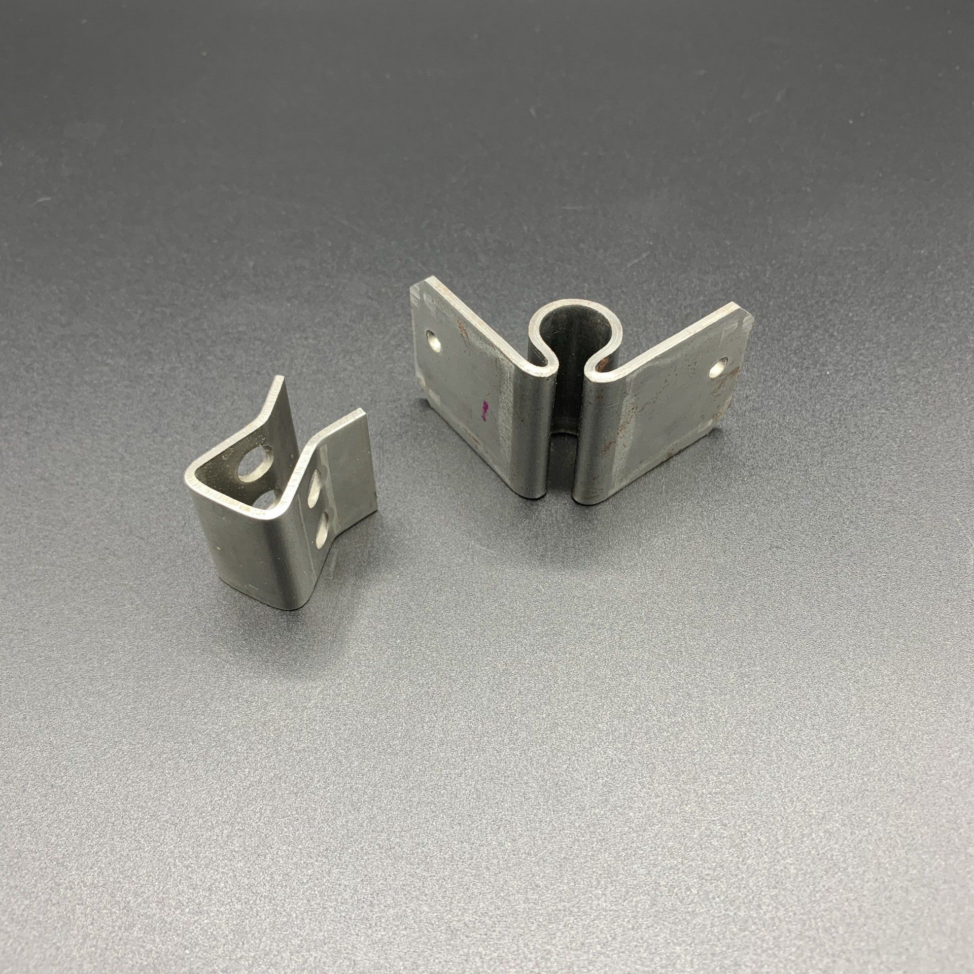 Two metal clips are sitting on a gray surface.