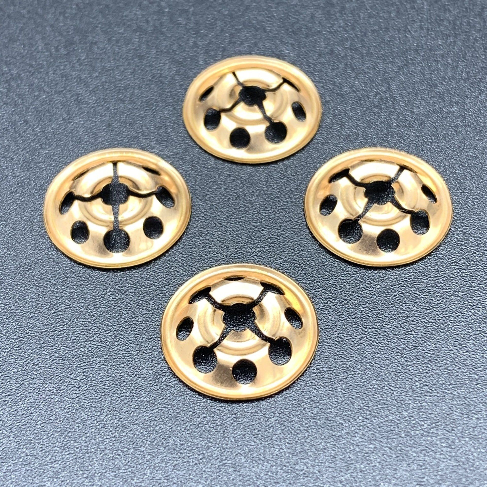 Four gold buttons are sitting on a black surface
