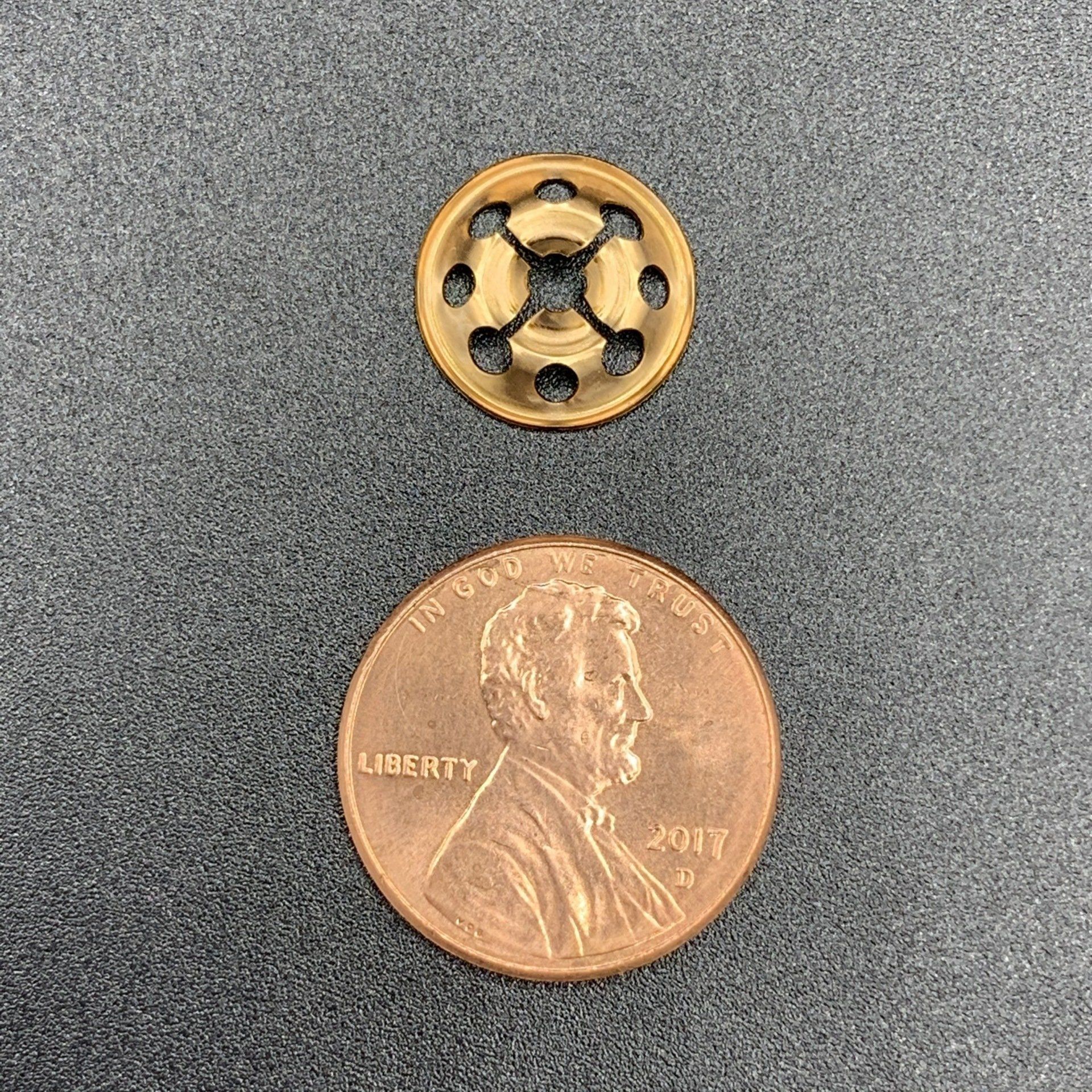 A close up of a penny and a button on a table.