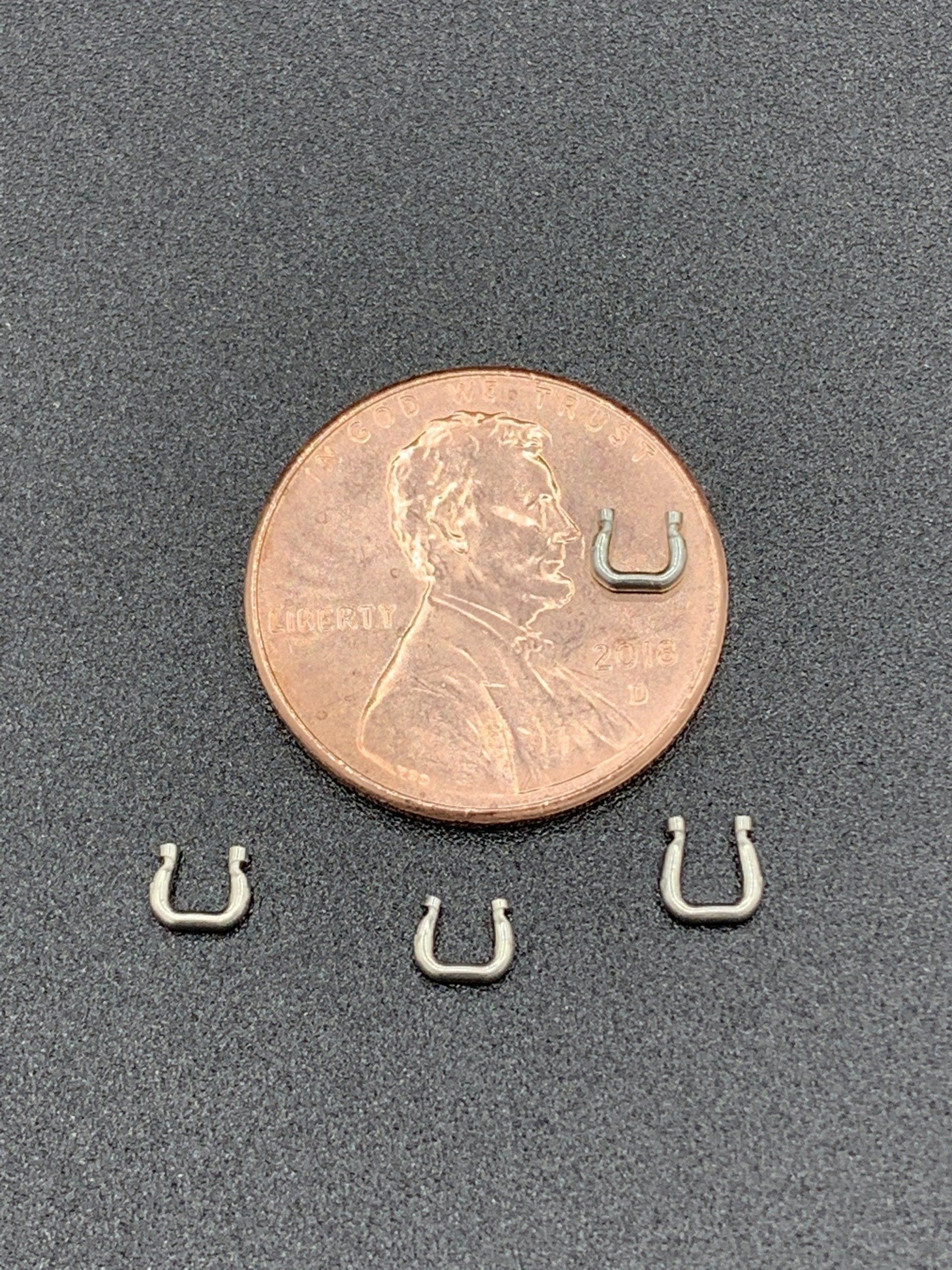 A penny is sitting next to three horseshoe earrings.