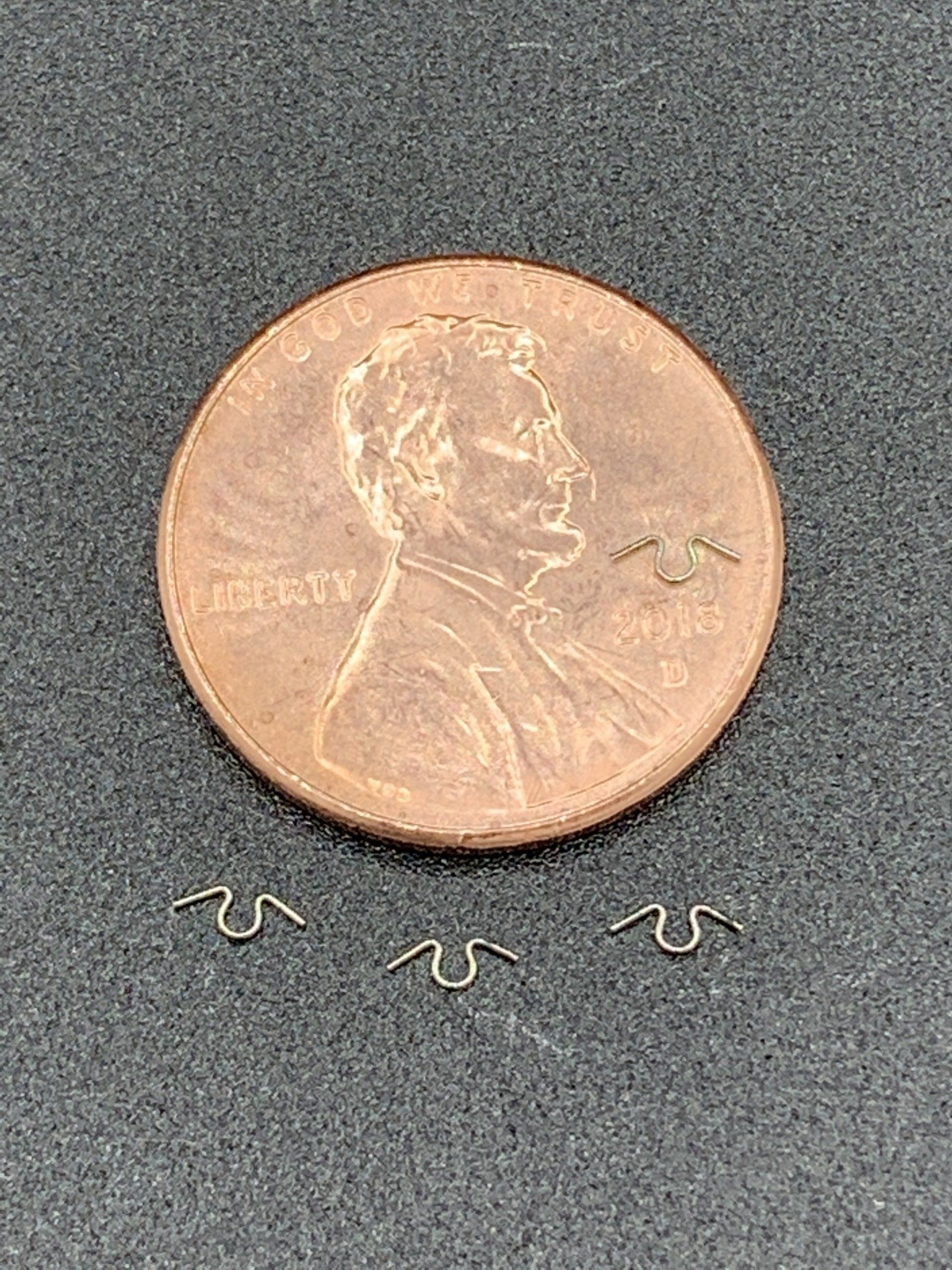 A penny is sitting on top of a table next to a pair of earrings.