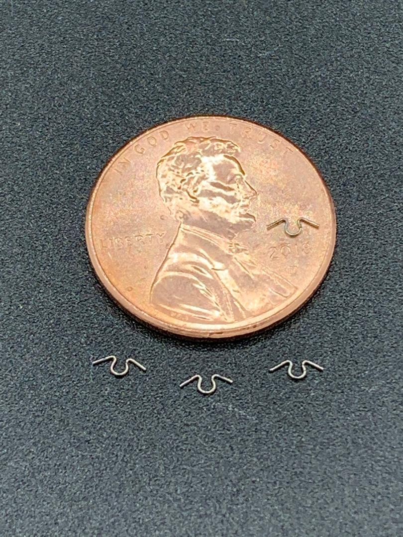 A penny is sitting on top of a table next to a pair of earrings.