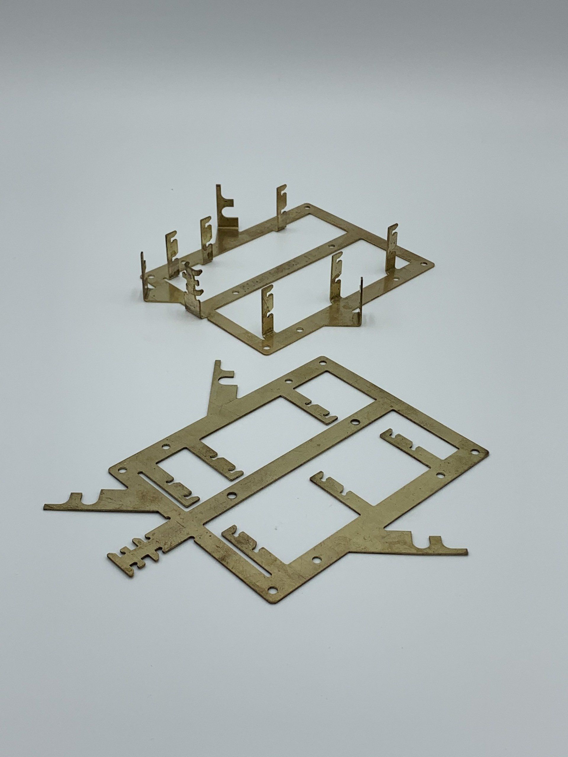 Two pieces of metal are sitting on a white surface.