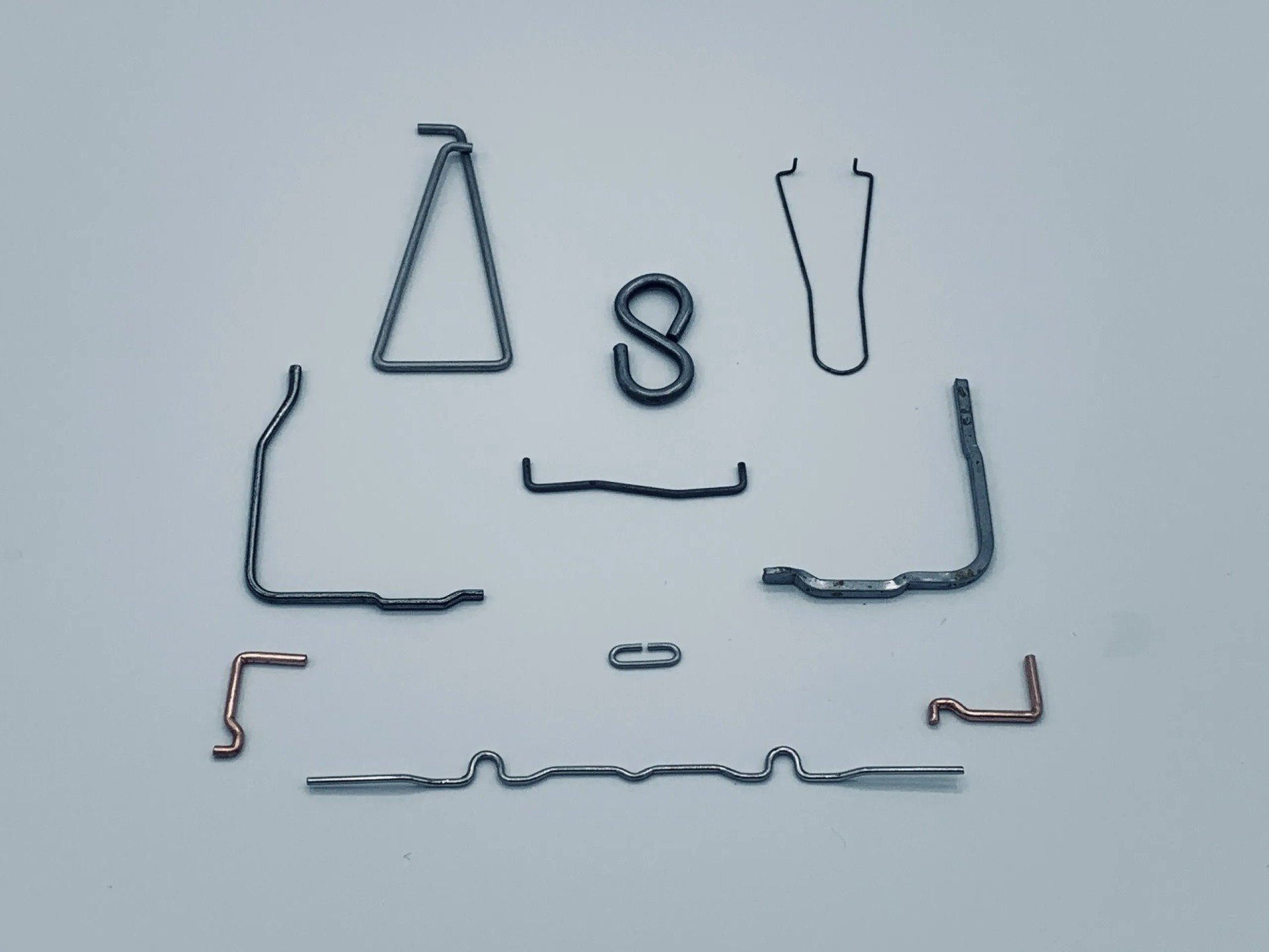 A bunch of different shaped wire pieces on a white surface