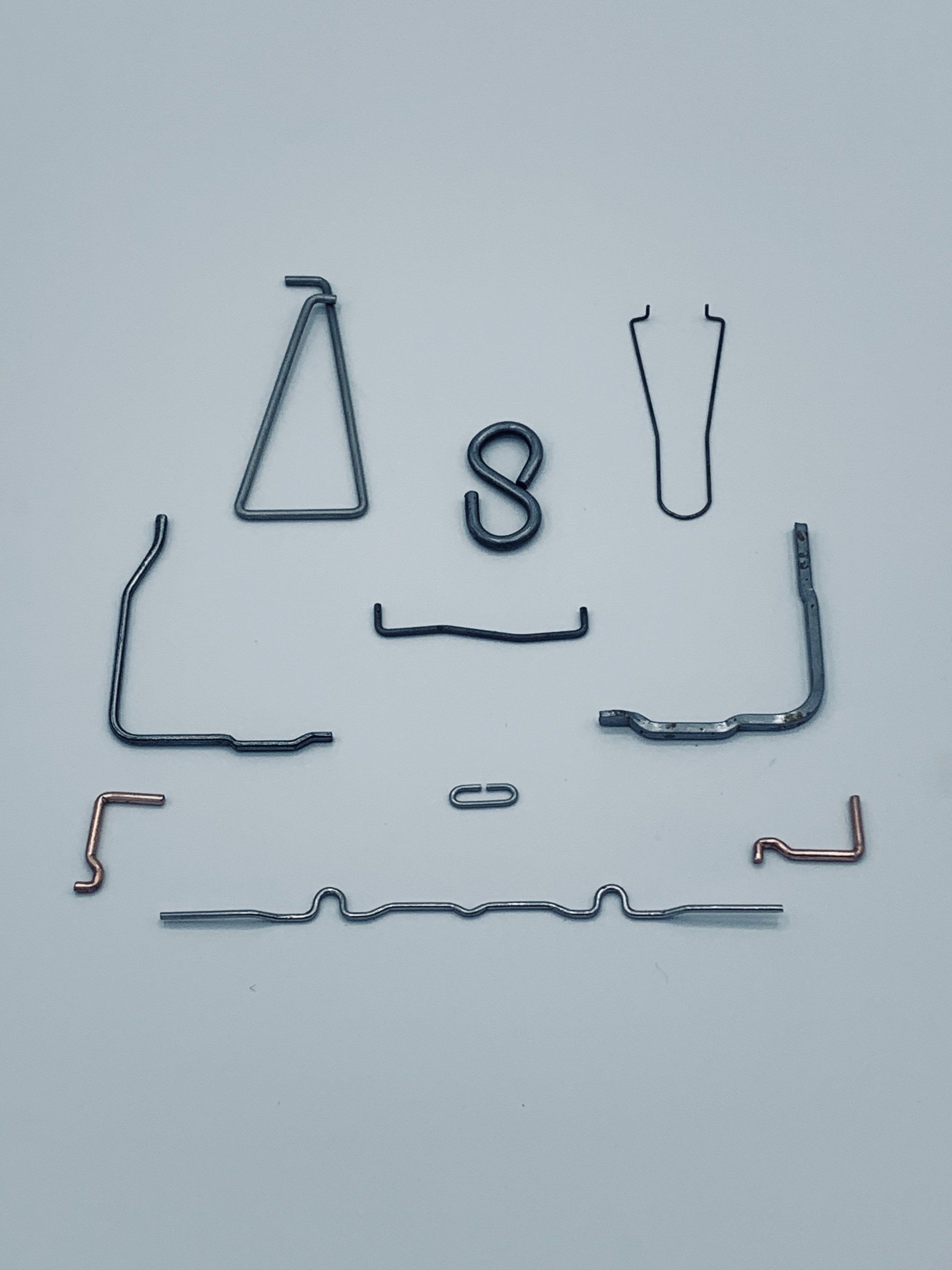 A bunch of different shaped wire clips on a white surface