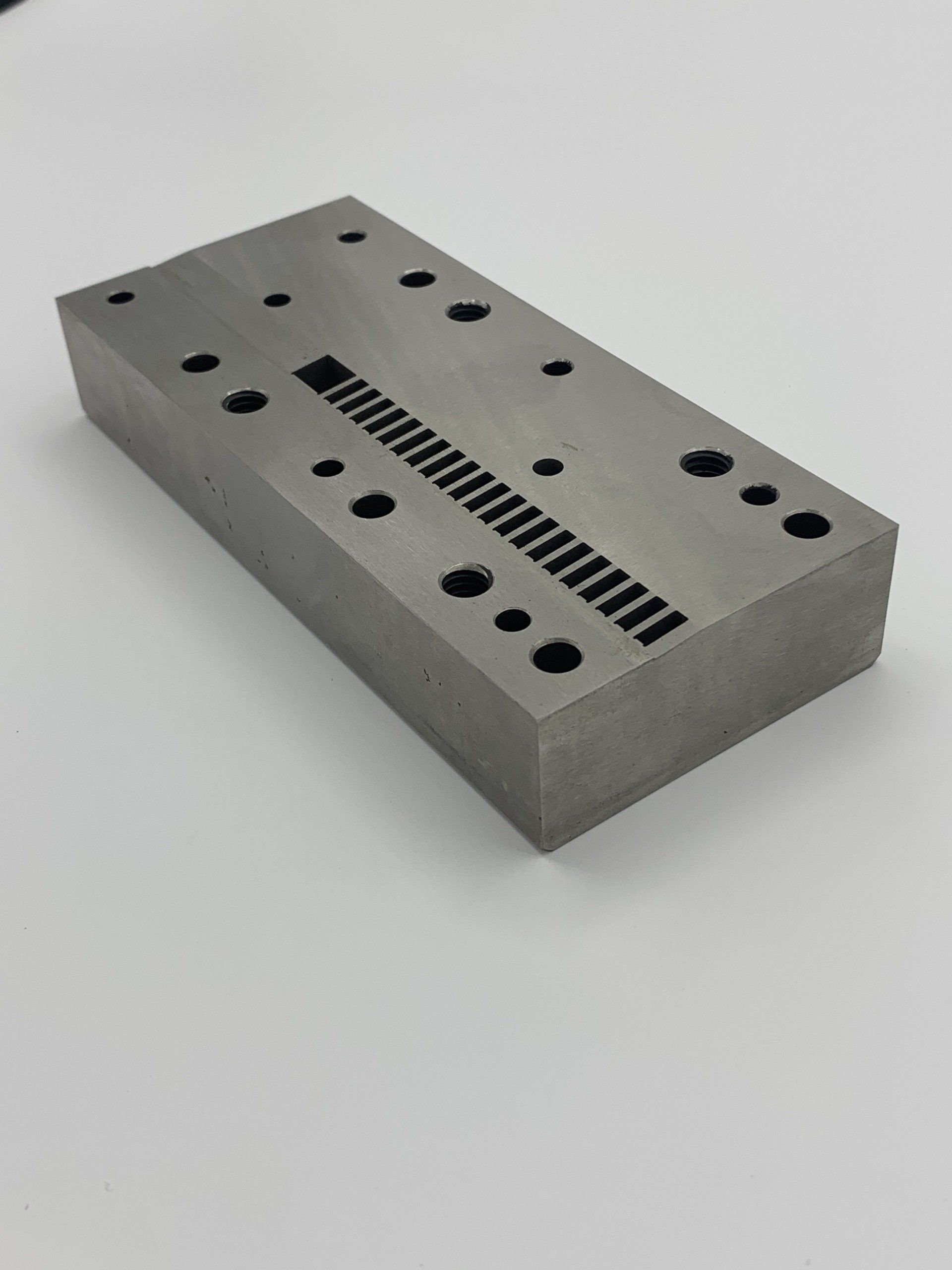 A piece of metal with holes in it is sitting on a white surface.