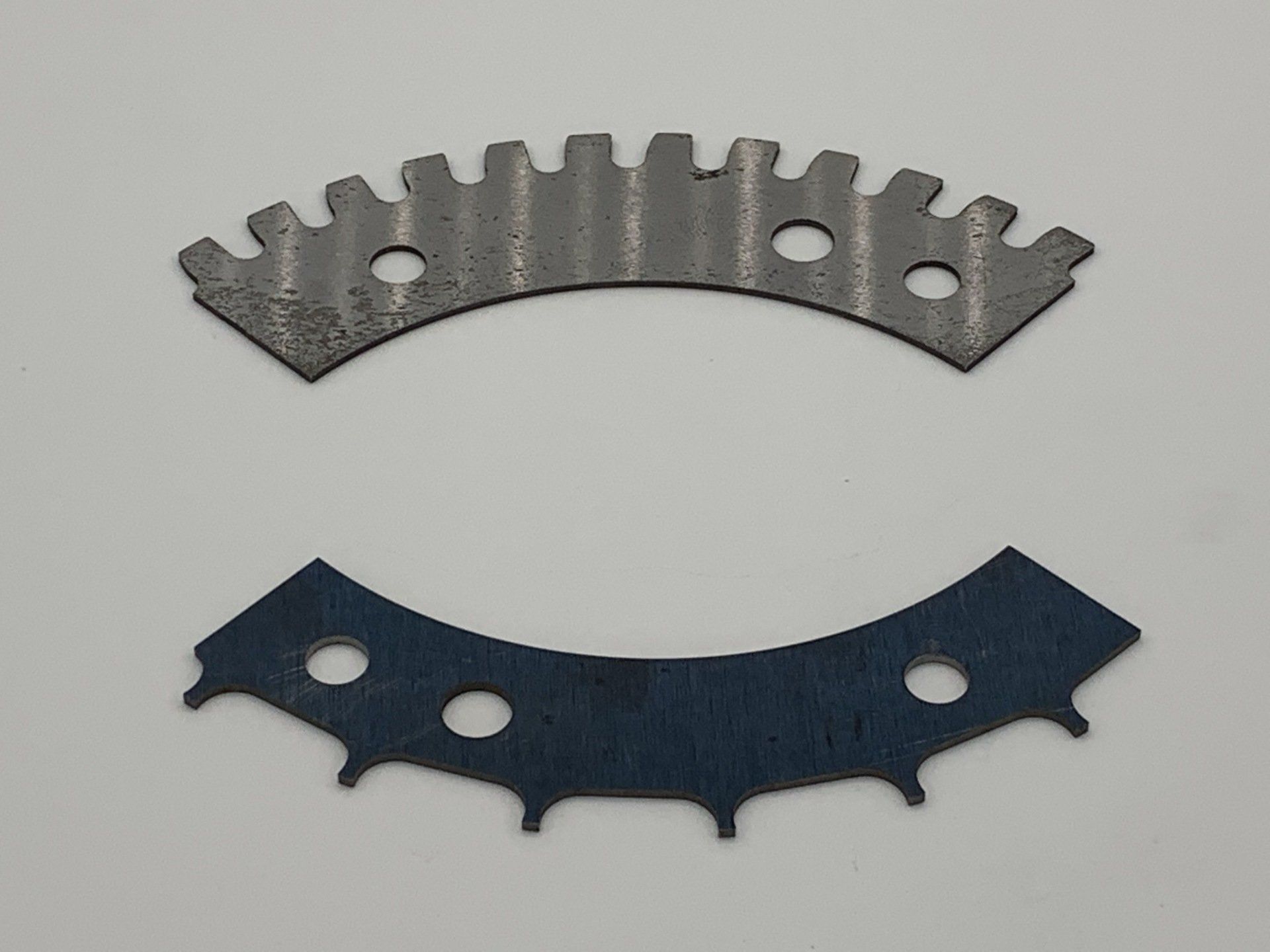 Two pieces of metal with holes in them on a white surface