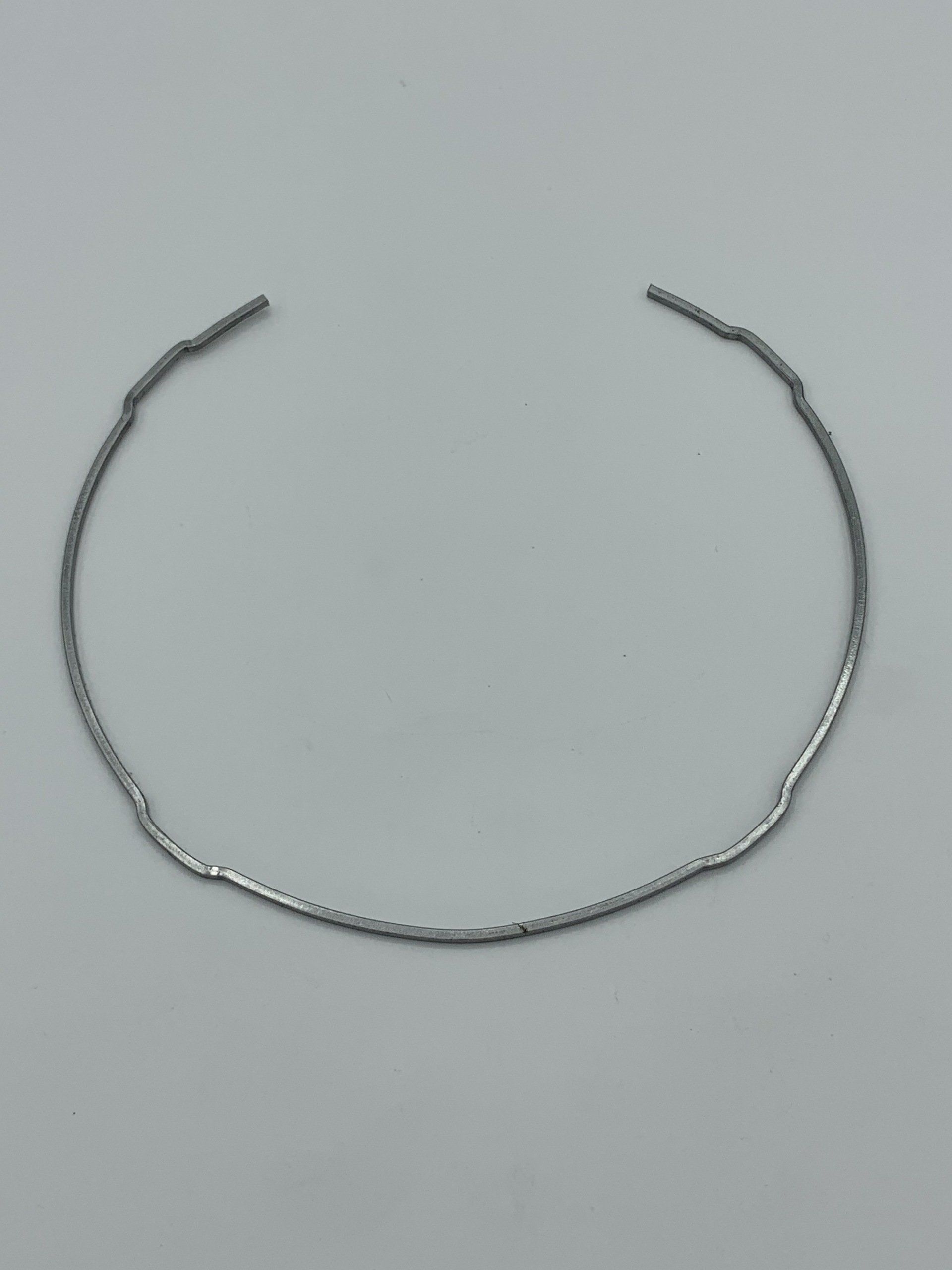 A close up of a silver bracelet on a white surface.