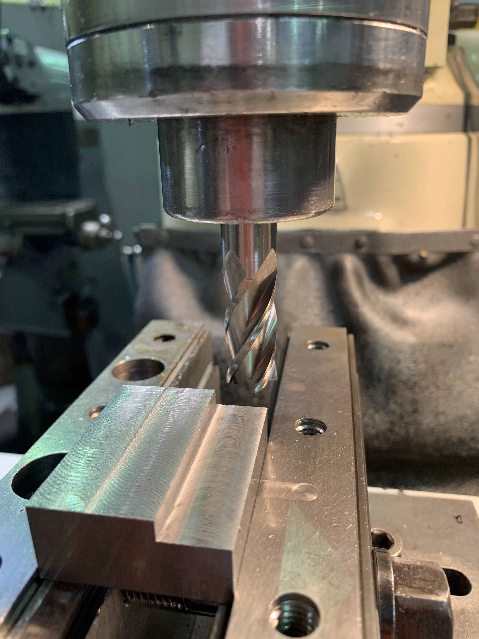 A machine is cutting a piece of metal with a drill bit.