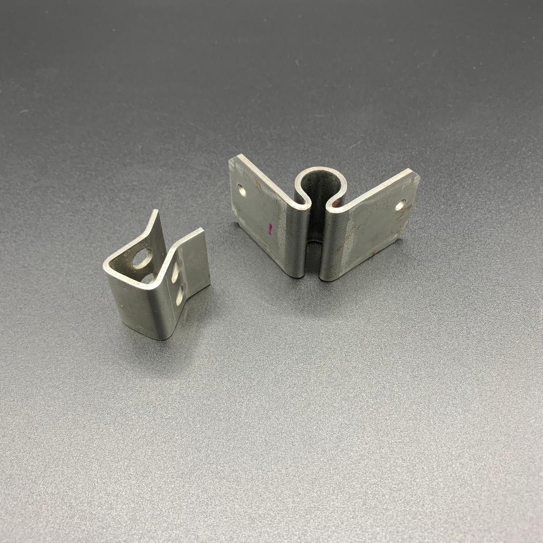 Two metal clips are sitting on a gray surface.