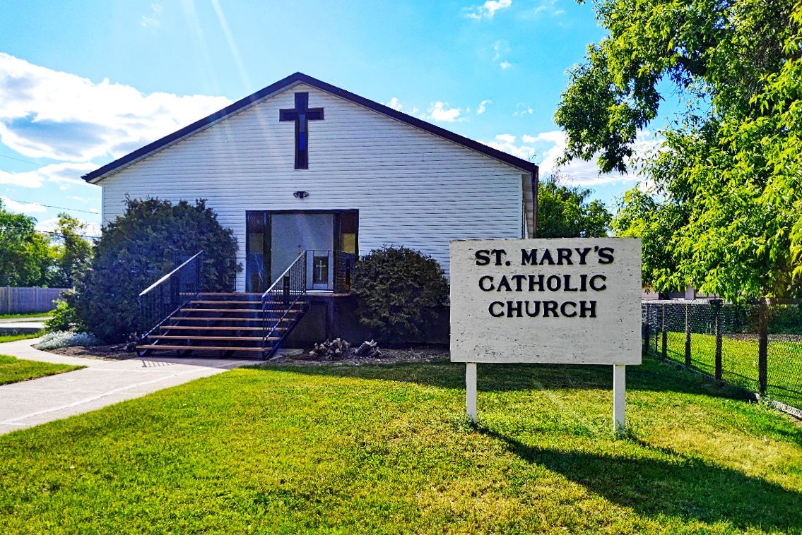 A white church with a sign in front of it that says `` st. mary 's catholic church ''.