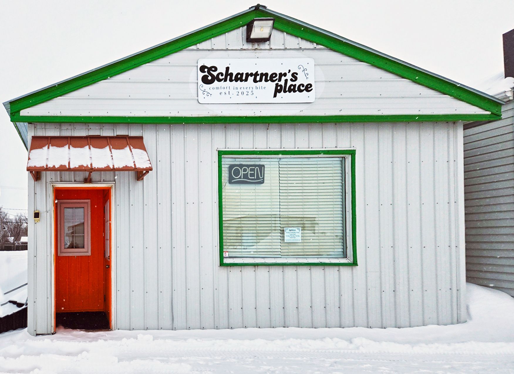 A white building with a green roof and a red door