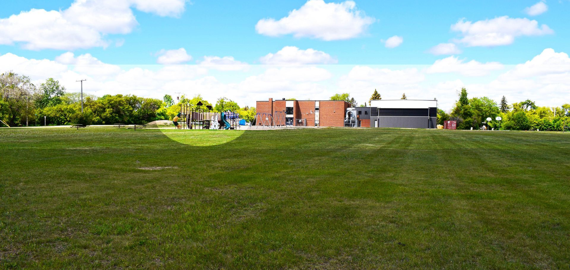 A large grassy field with a building in the background.