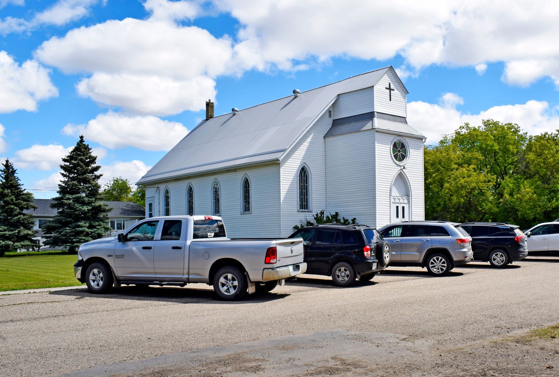 A row of cars are parked in front of a church