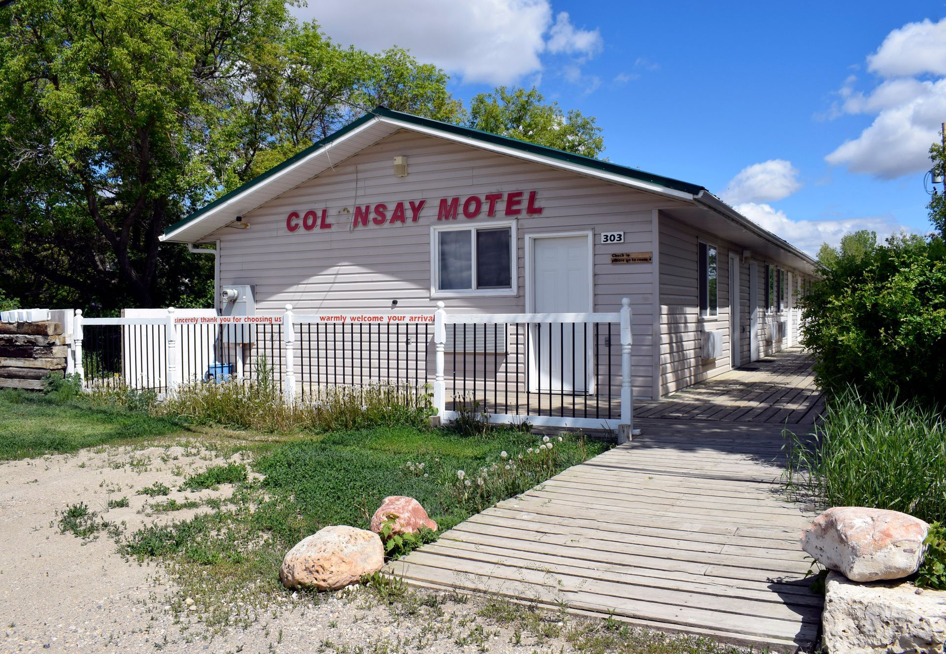 A small white house with a red sign that says col nsay motel