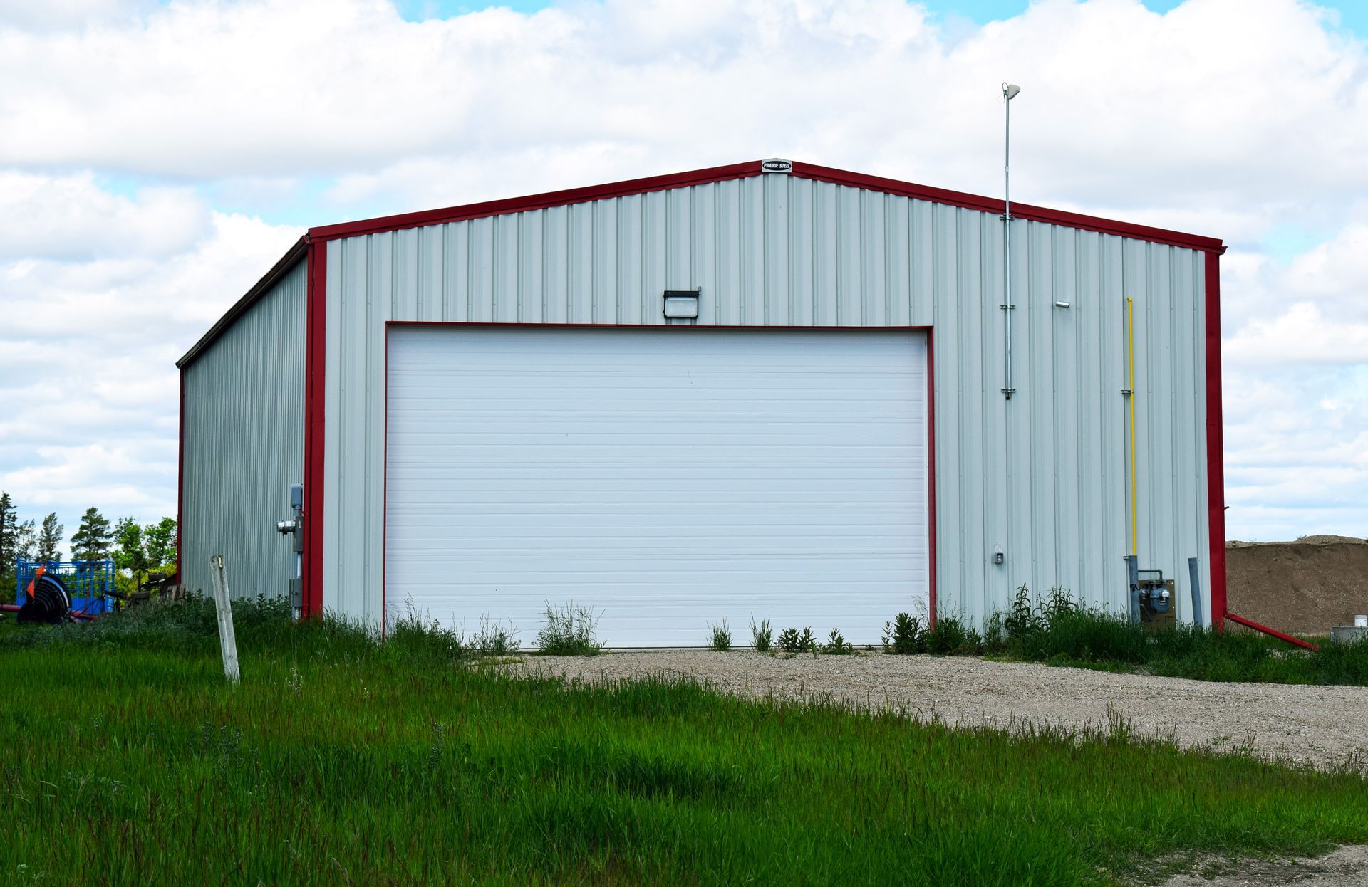 A white and red metal building with a white garage door.
