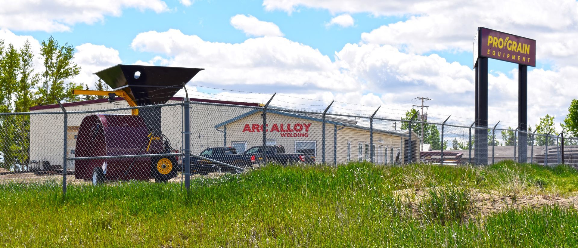 A large building with a fence around it is sitting in the middle of a grassy field.