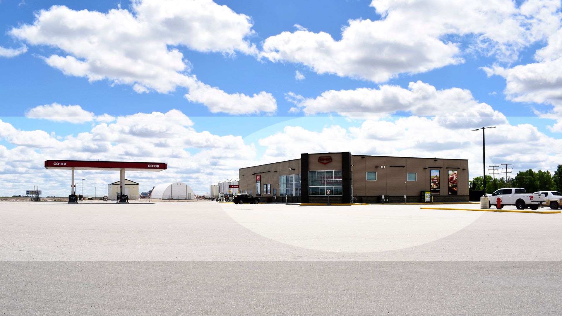 An empty parking lot with a gas station in the background