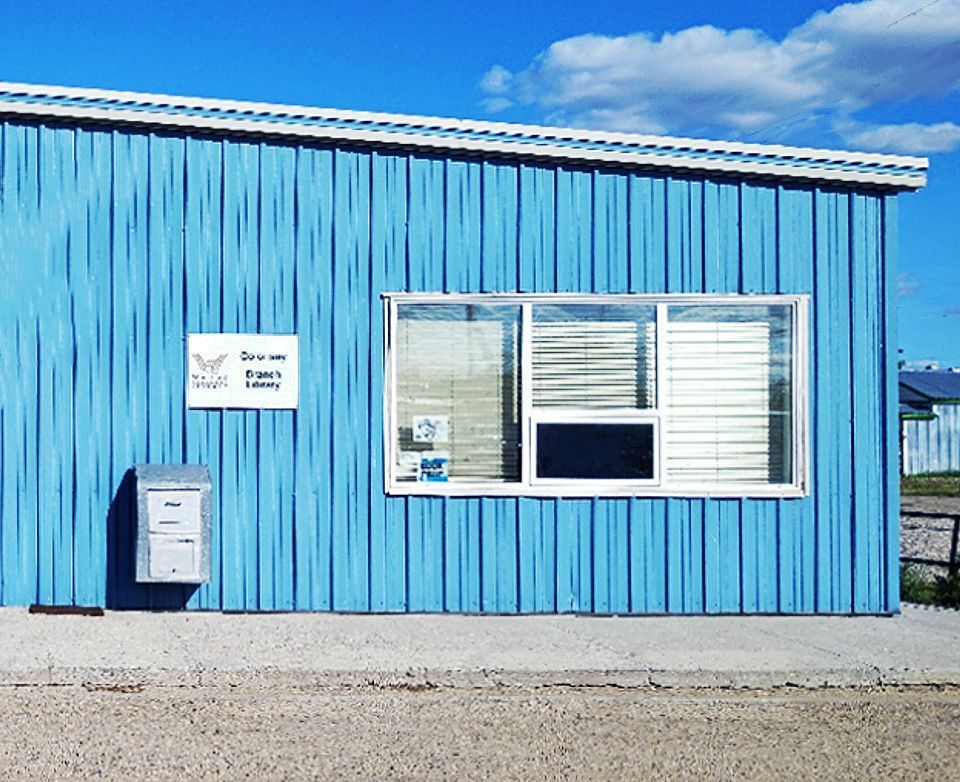 A sign for nutrien ag solutions is in the dirt in front of a building.