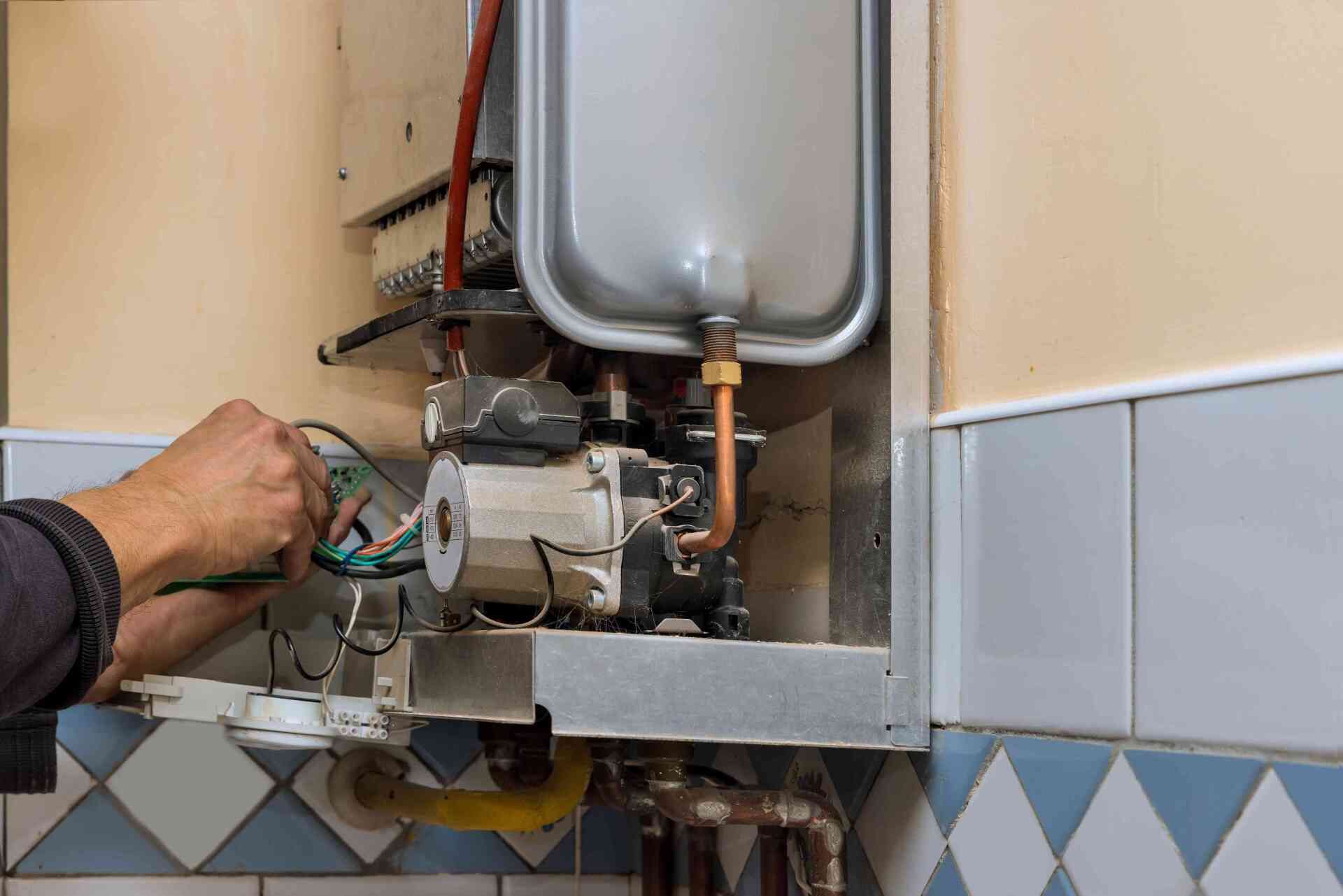 Technician repairing a wall-mounted gas boiler with tools in a tiled utility room