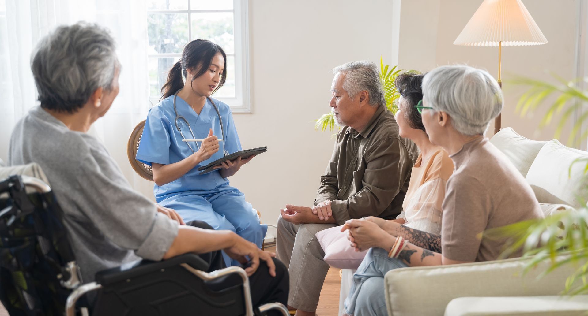 A nurse is talking to a group of elderly people in a living room.