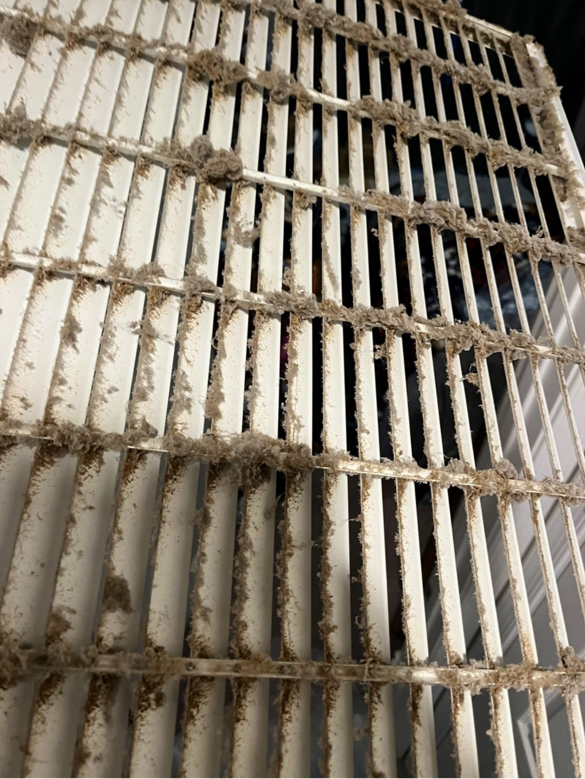 A close up of a dirty grill with a lot of holes in it.