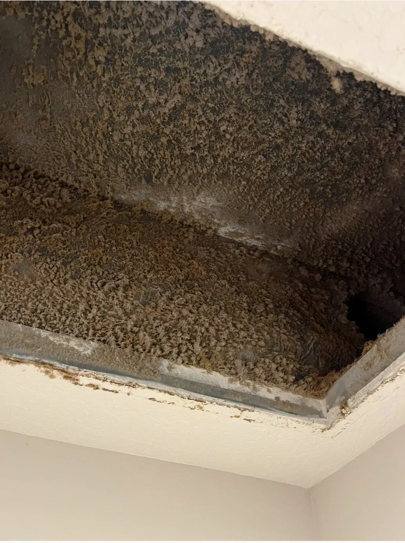 A close up of a dirty air vent in a room.