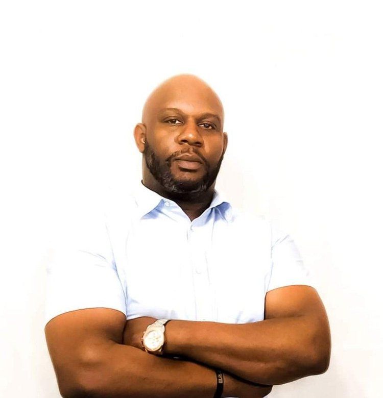 A bald man with a beard is standing with his arms crossed and wearing a watch.