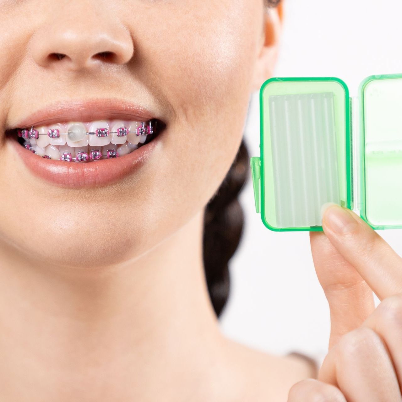 A woman with braces on her teeth is holding a green box