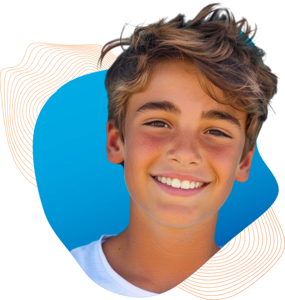 A young boy is smiling in front of a blue background.