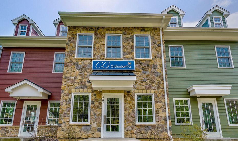 A row of houses are lined up in a row with a blue sign on the front of one of the houses.