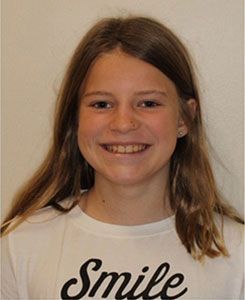 A young girl wearing a white shirt that says smile