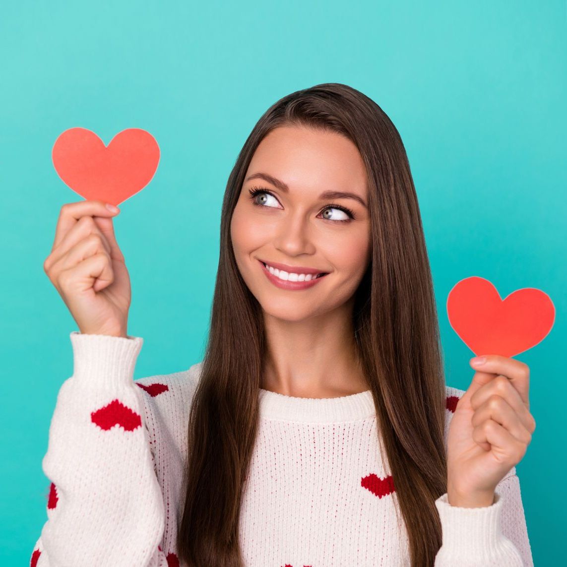 A woman is holding two red hearts in her hands.