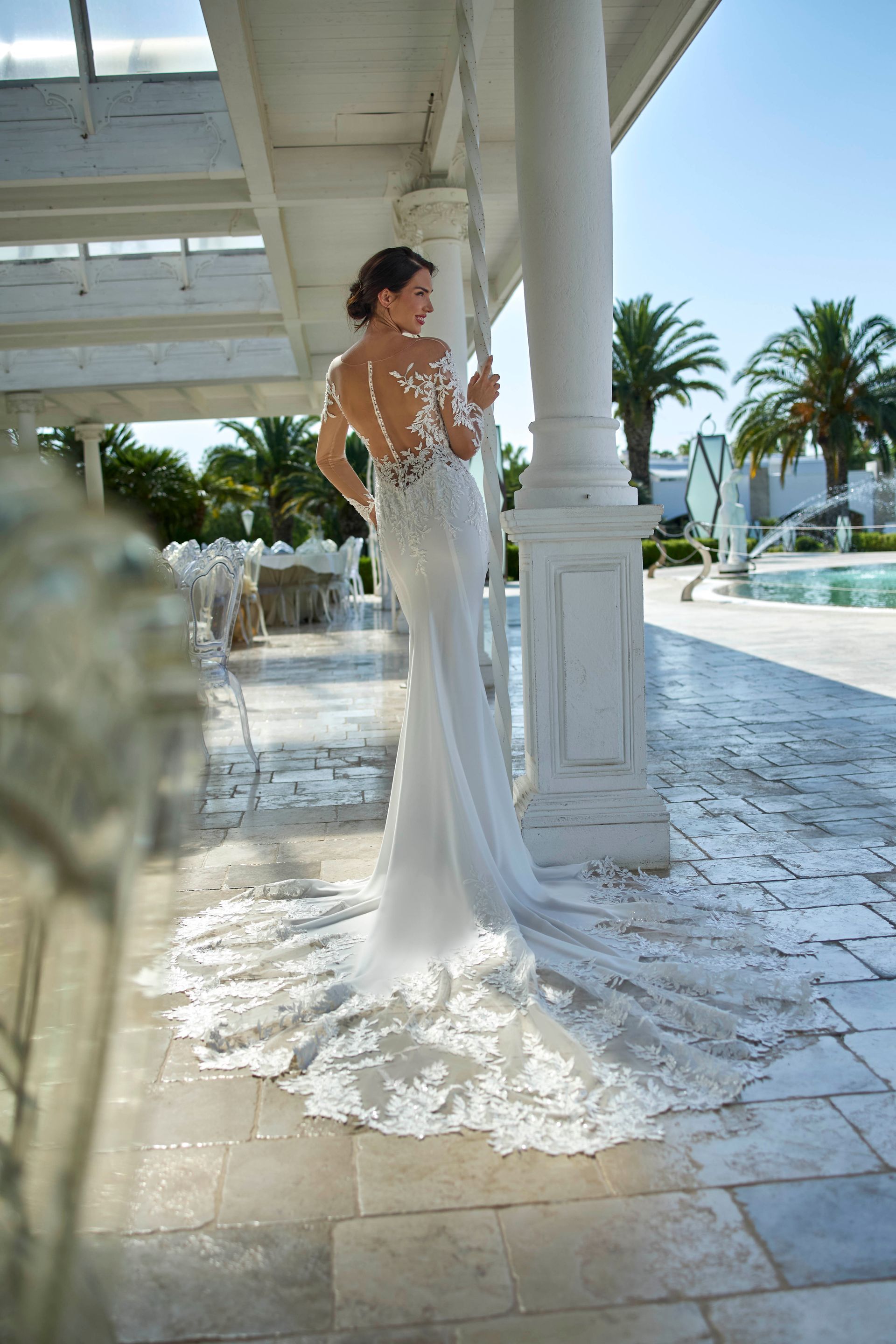 Donna in abito da sposa bianco con dettagli in pizzo, all'aperto.