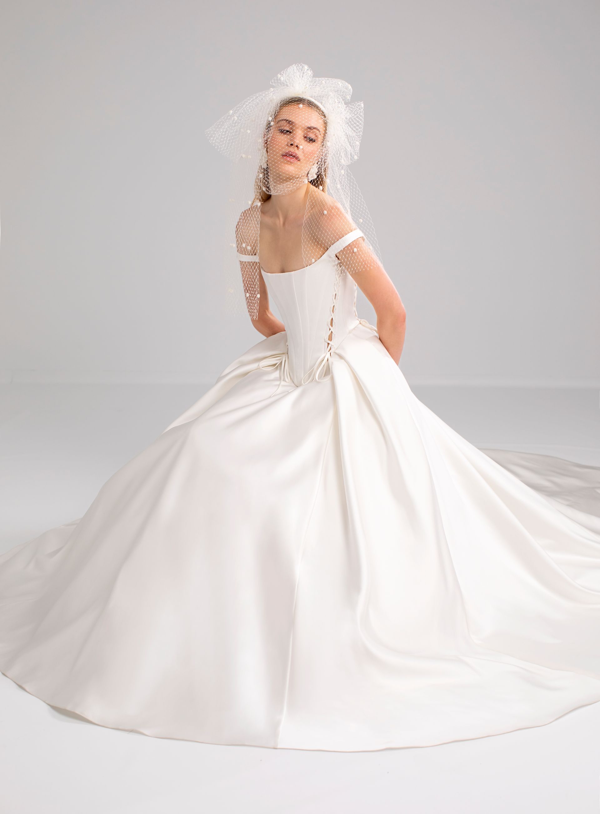 Donna in abito da sposa bianco con gonna ampia e velo.