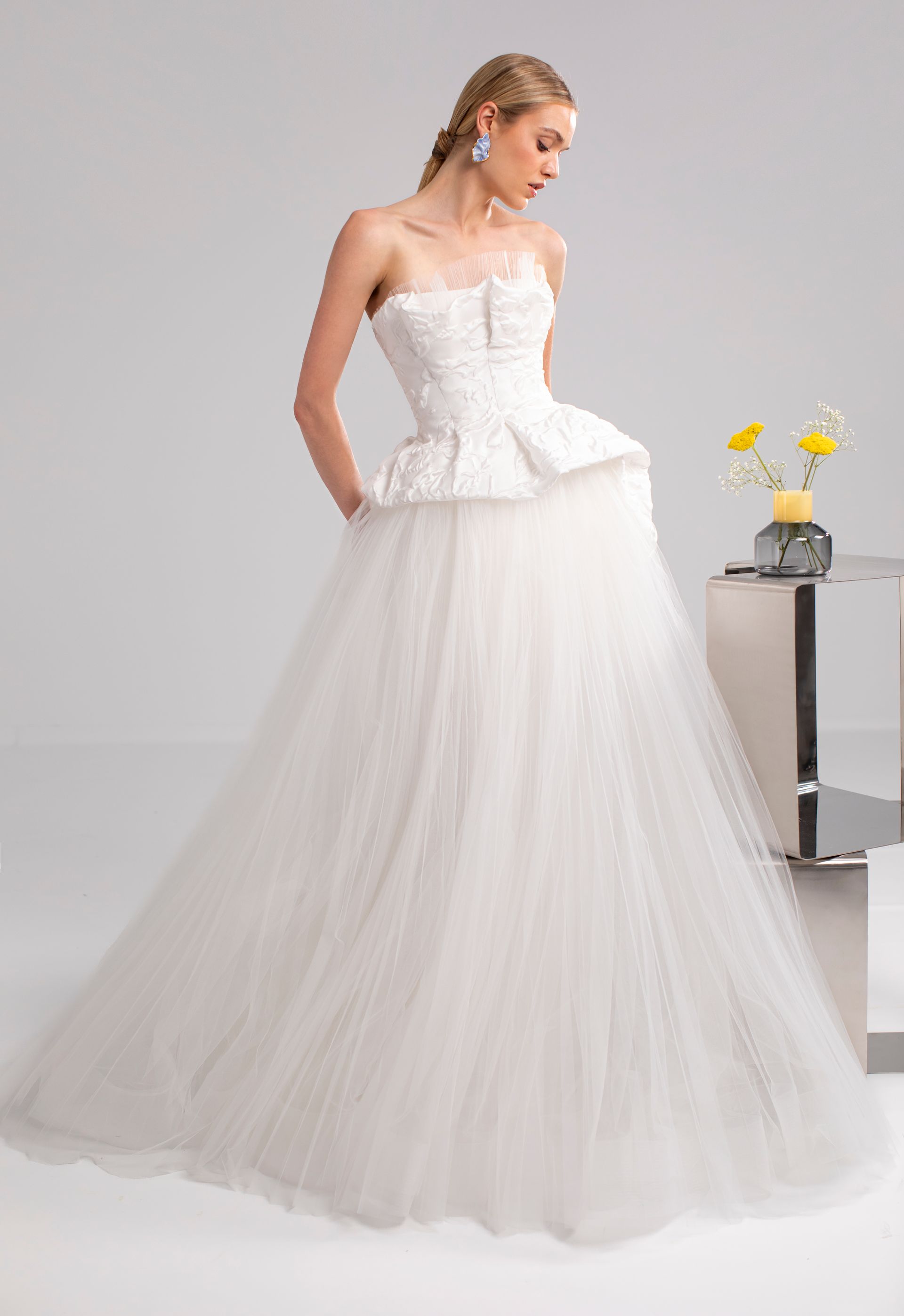 Donna che indossa un abito da sposa bianco senza spalline con corpetto a peplo e gonna in tulle