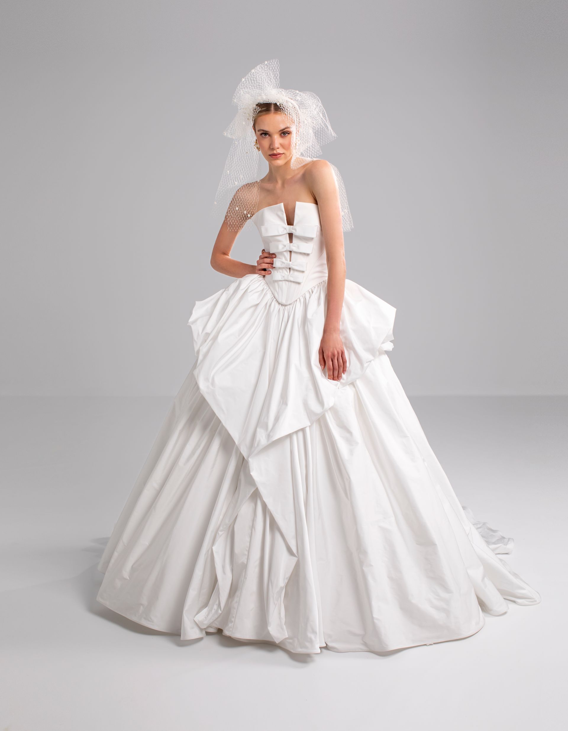 Donna in abito da sposa bianco con gonna ampia e corpetto elaborato, con velo.