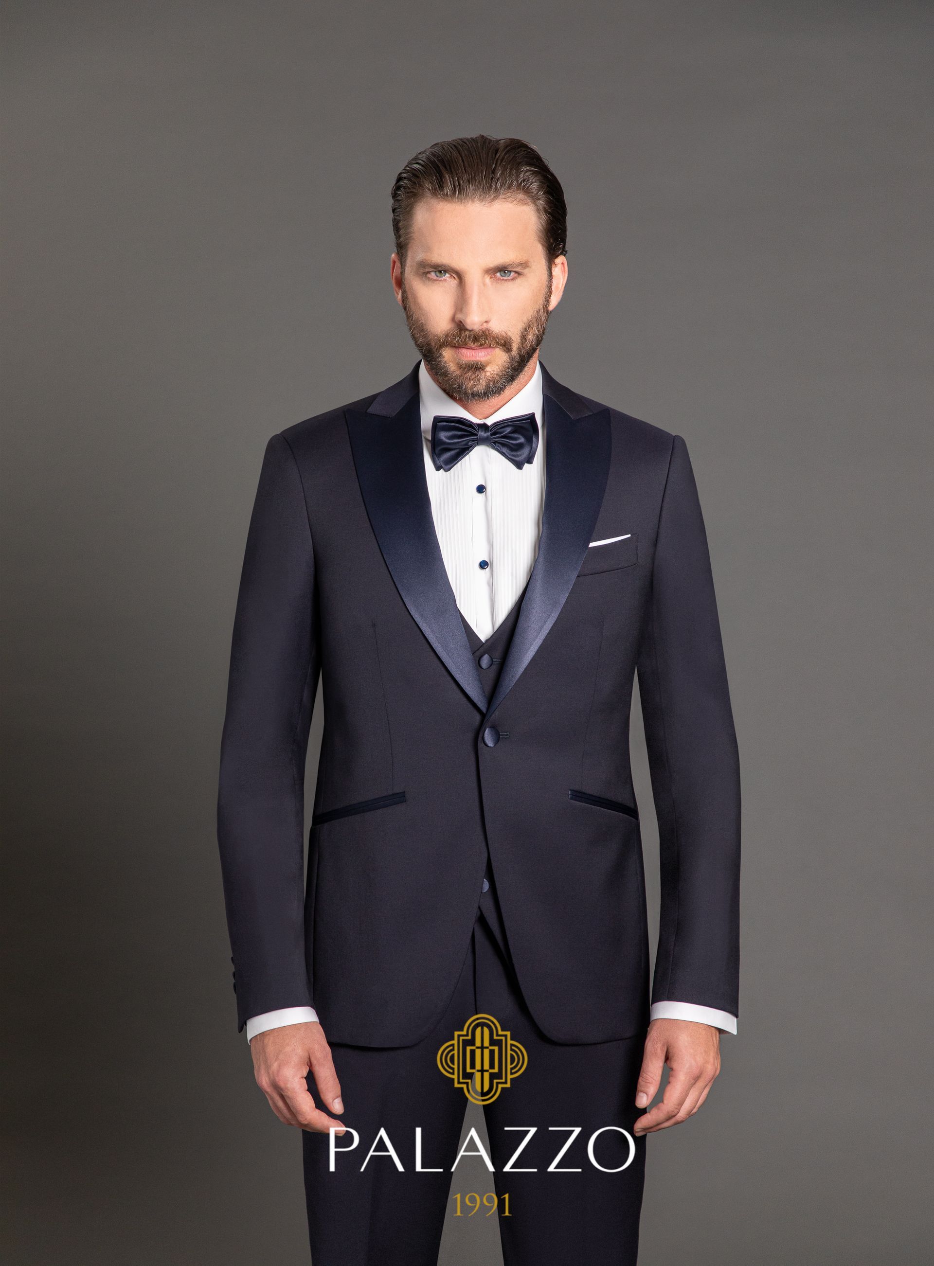 Uomo in smoking blu navy, papillon nero e camicia bianca; abito formale per un evento.
