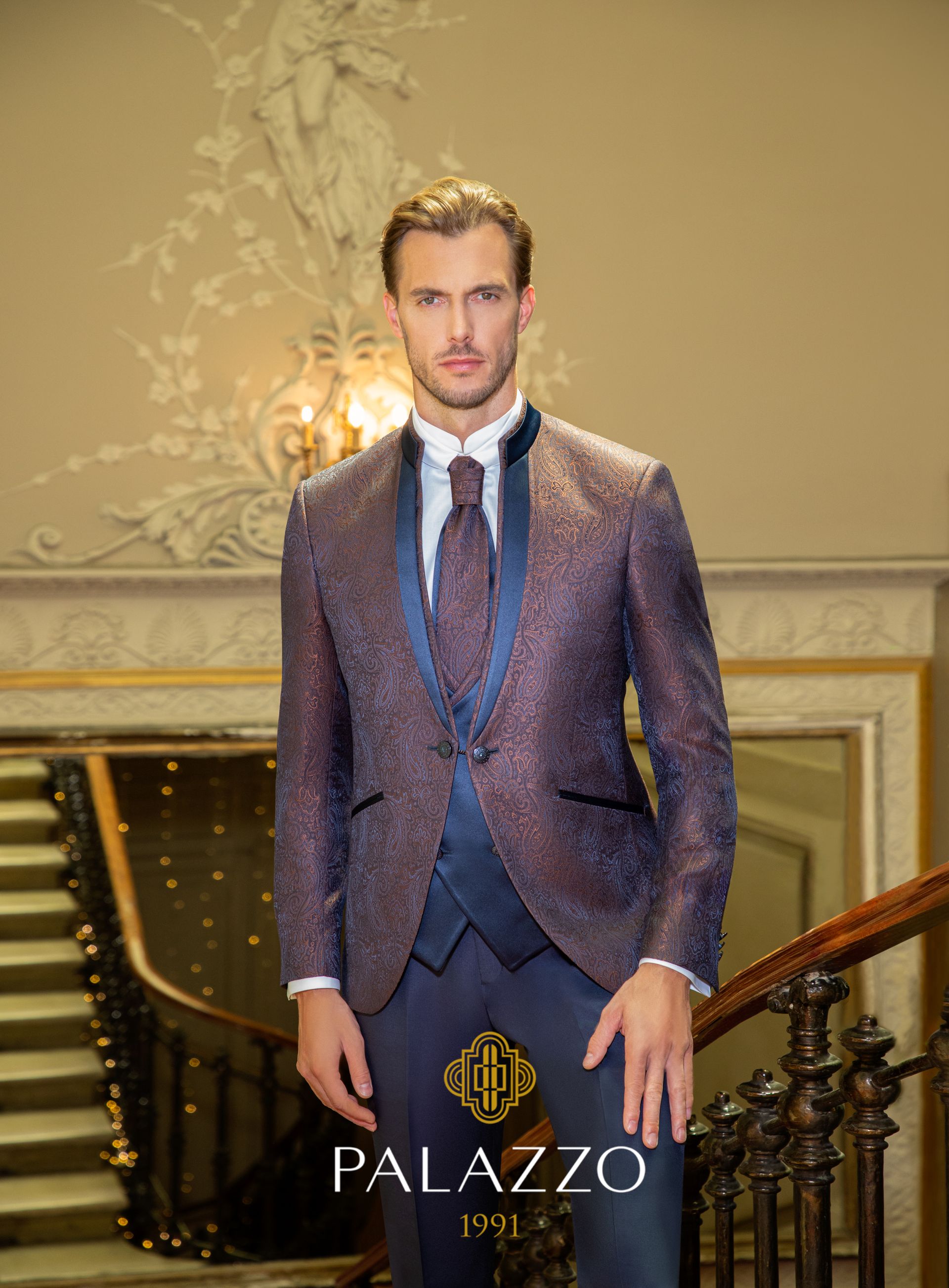 Uomo in abito viola scintillante, in piedi sulle scale, ambiente elegante.