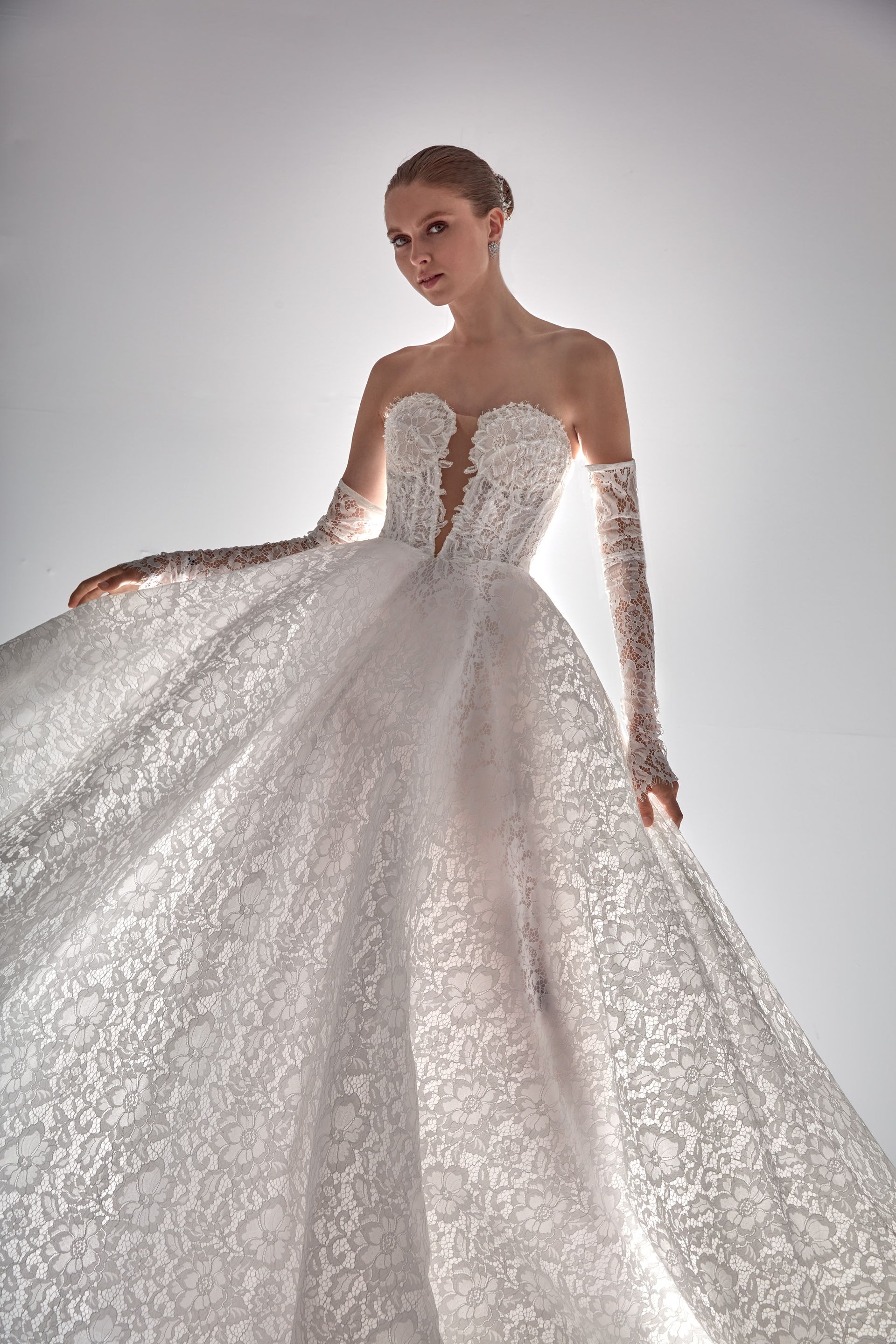 Donna in abito bianco senza spalline con lunghi guanti di pizzo, in posa.