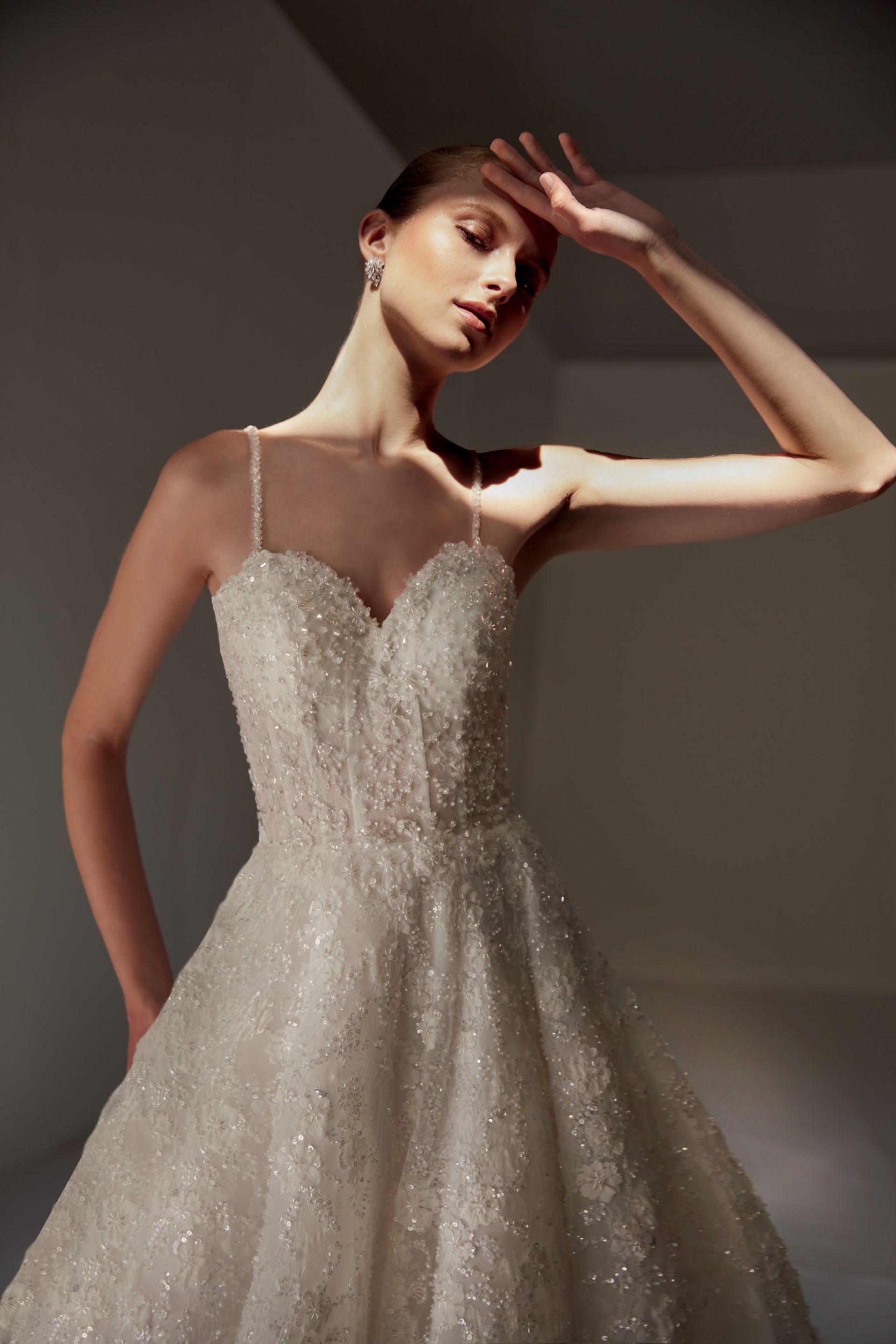 Donna con un abito da sposa scintillante che si ripara gli occhi, illuminata dalla luce del sole.