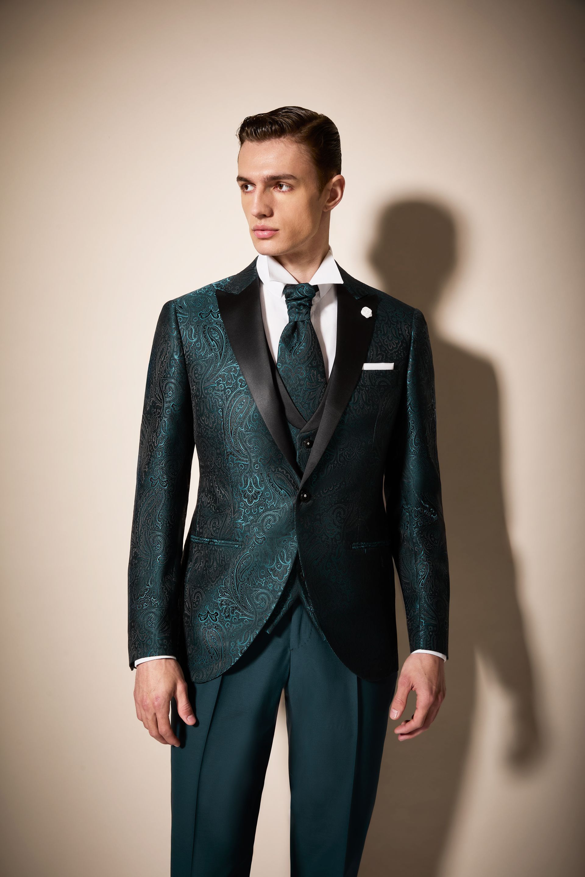 Uomo in abito scintillante color verde acqua con risvolti neri, gilet, cravatta e camicia bianca