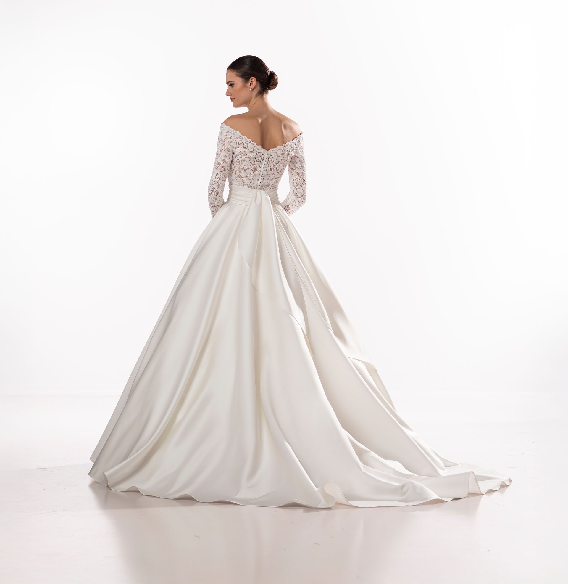 Donna con abito da sposa bianco, vista posteriore. Corpetto in pizzo con spalle scoperte e maniche lunghe