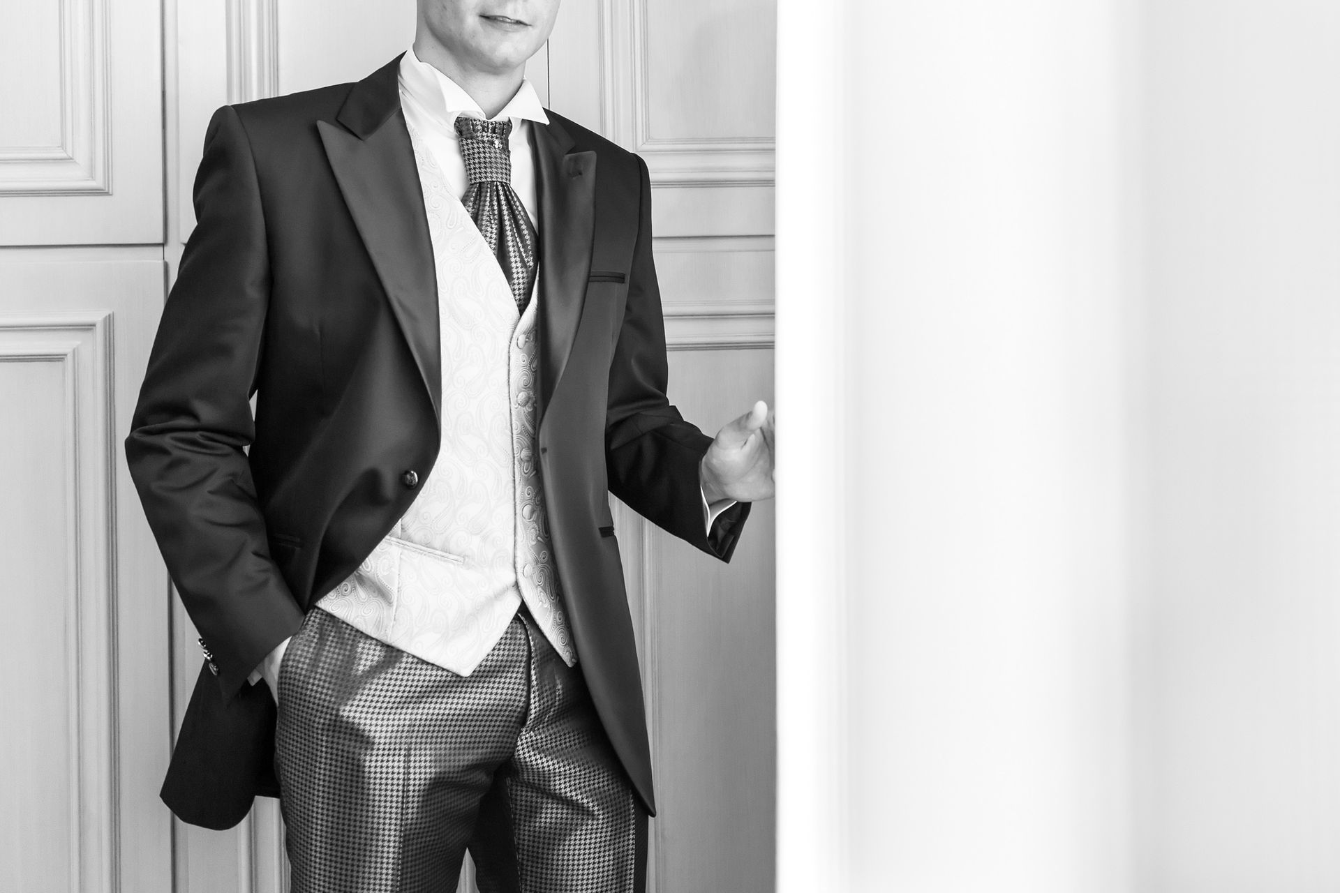 Donna che prova l'abito da sposa; stilista che lo sistema. Negozio di abiti da sposa, luce del sole.