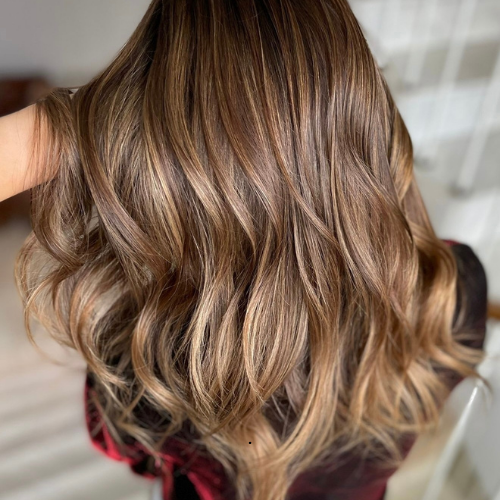 A woman with long brown hair is wearing a plaid shirt.
